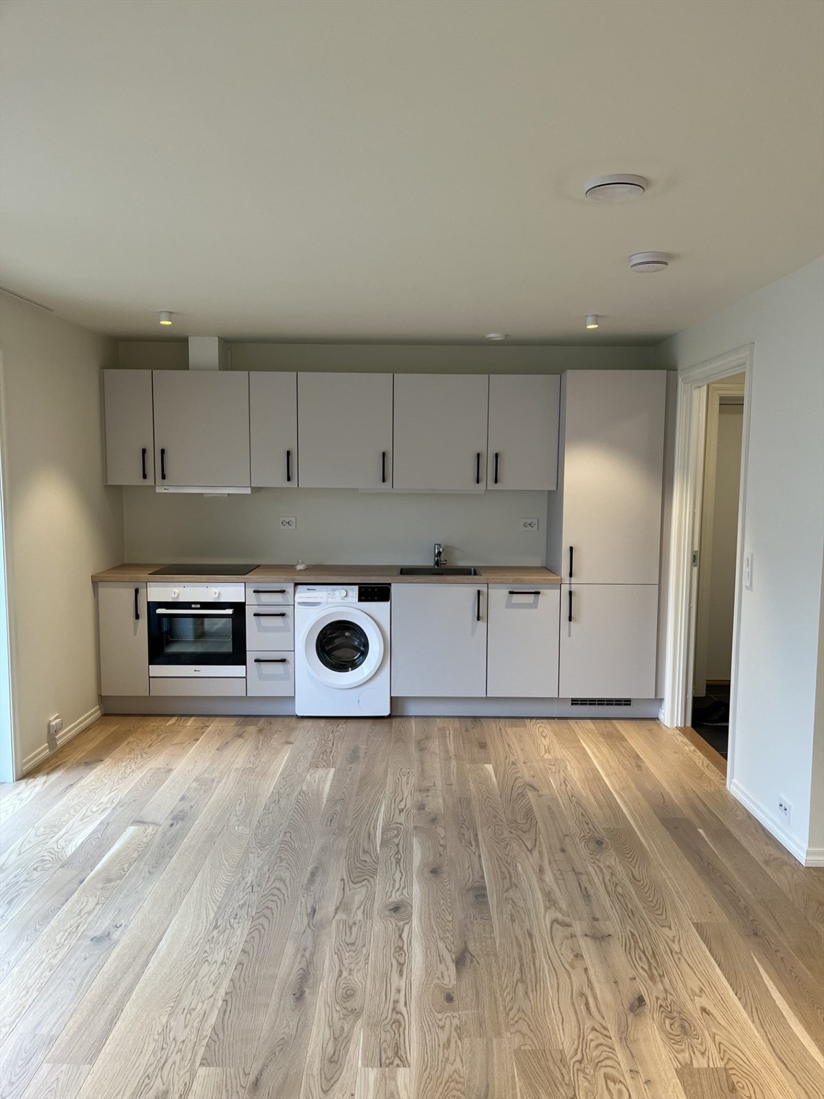 Lekkert kjøkken med god skap- og benkeplass. Opplegg for vaskemaskin på kjøkken. Galleribilde