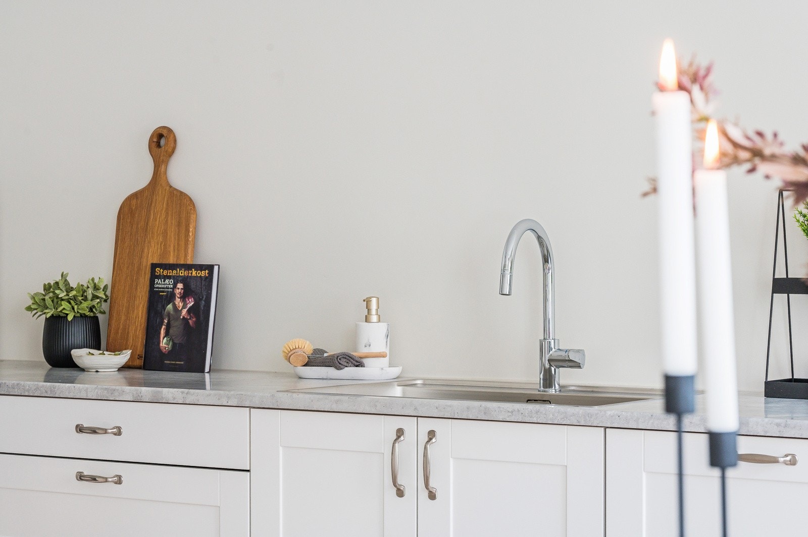 Det er benkeplate i laminat med grålig struktur og kum i rustfritt stål med et-greps armatur. Galleribilde