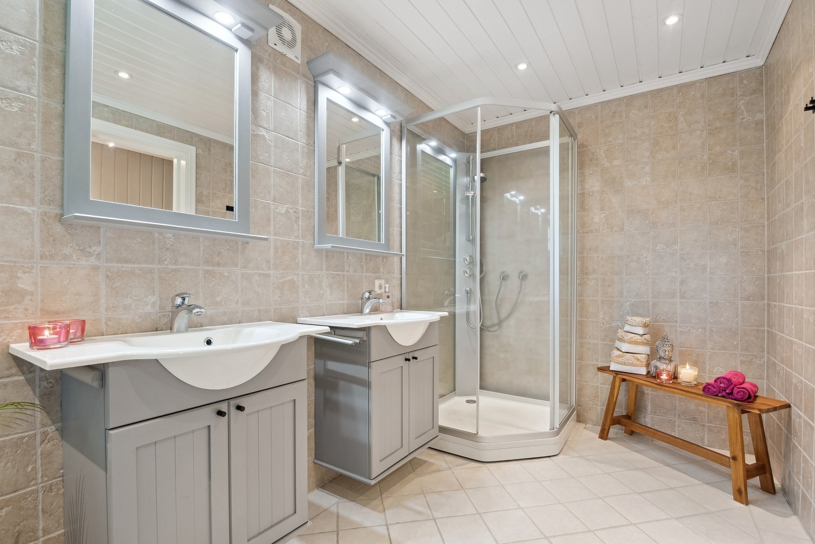 Flislagte overflater, moderne dusjkabinett og speil med belysning gir badet et innbydende uttrykk. Galleribilde