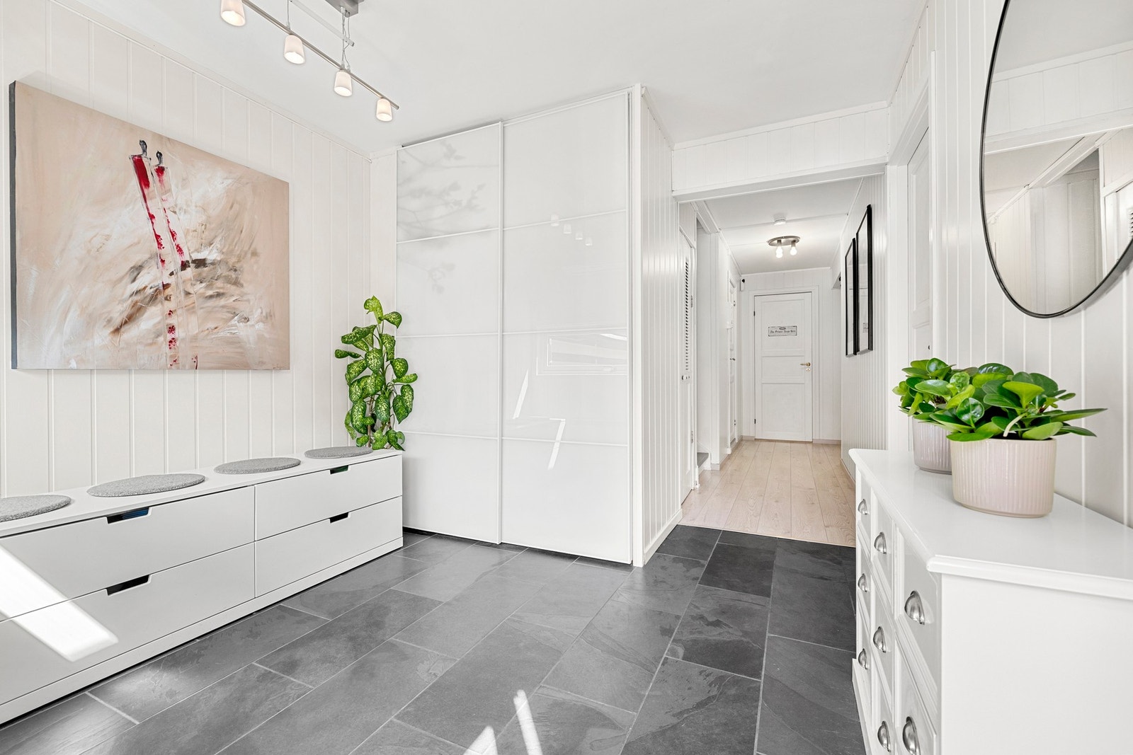 Romslig og innbydende entré med flislagt gulv og god oppbevaringsplass i skyvedørsgarderobe. Galleribilde