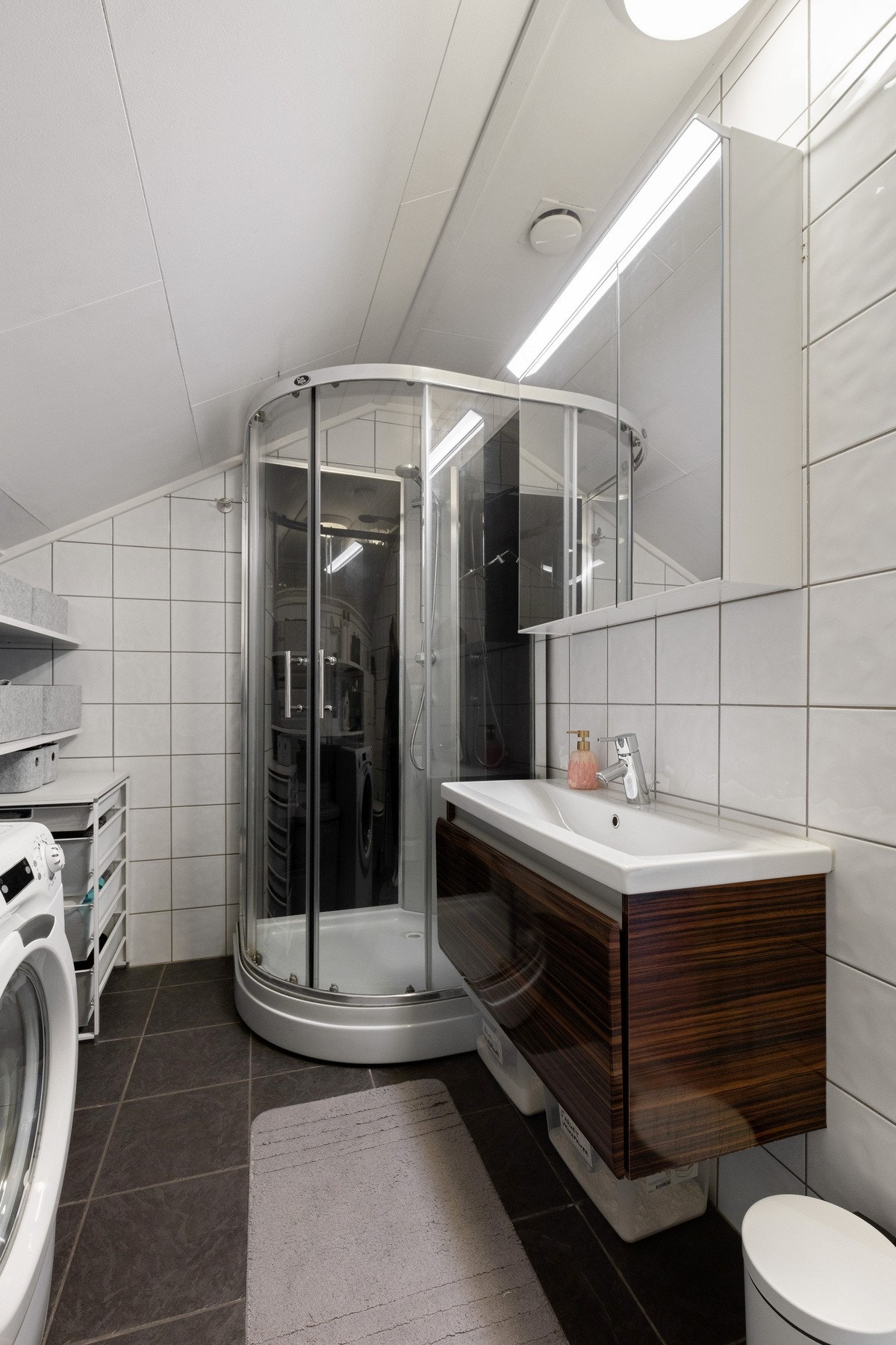 Flott baderom bestående av servant med underskuff, dusjkabinett og toalett Galleribilde