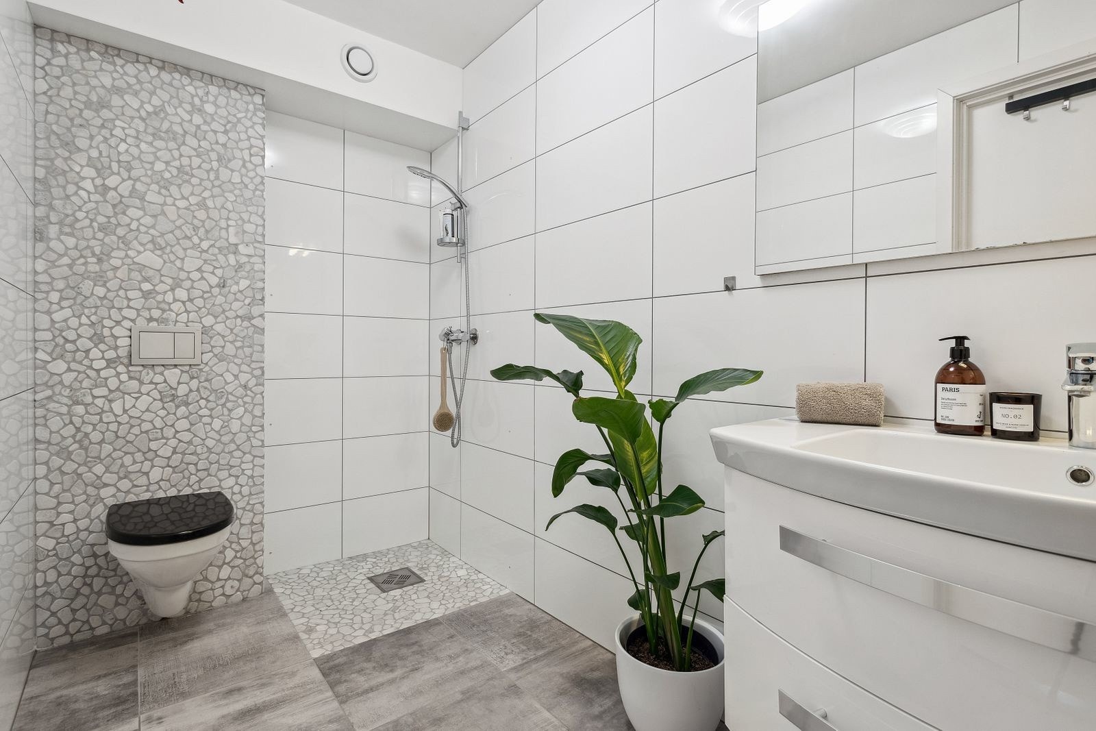 Helfliset bad med baderomsinnredning, speil med integrert belysning, dusjhjørne og vegghengt toalett Galleribilde