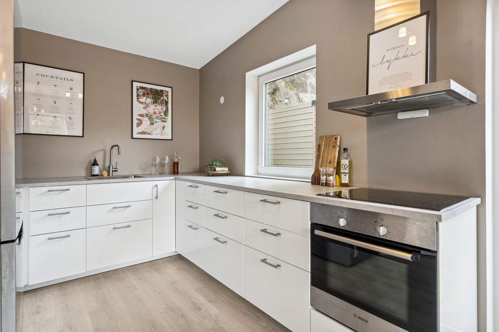 Kjøkkeninnredning utført med hvite høyglansfronter og benkeplate av laminat Galleribilde