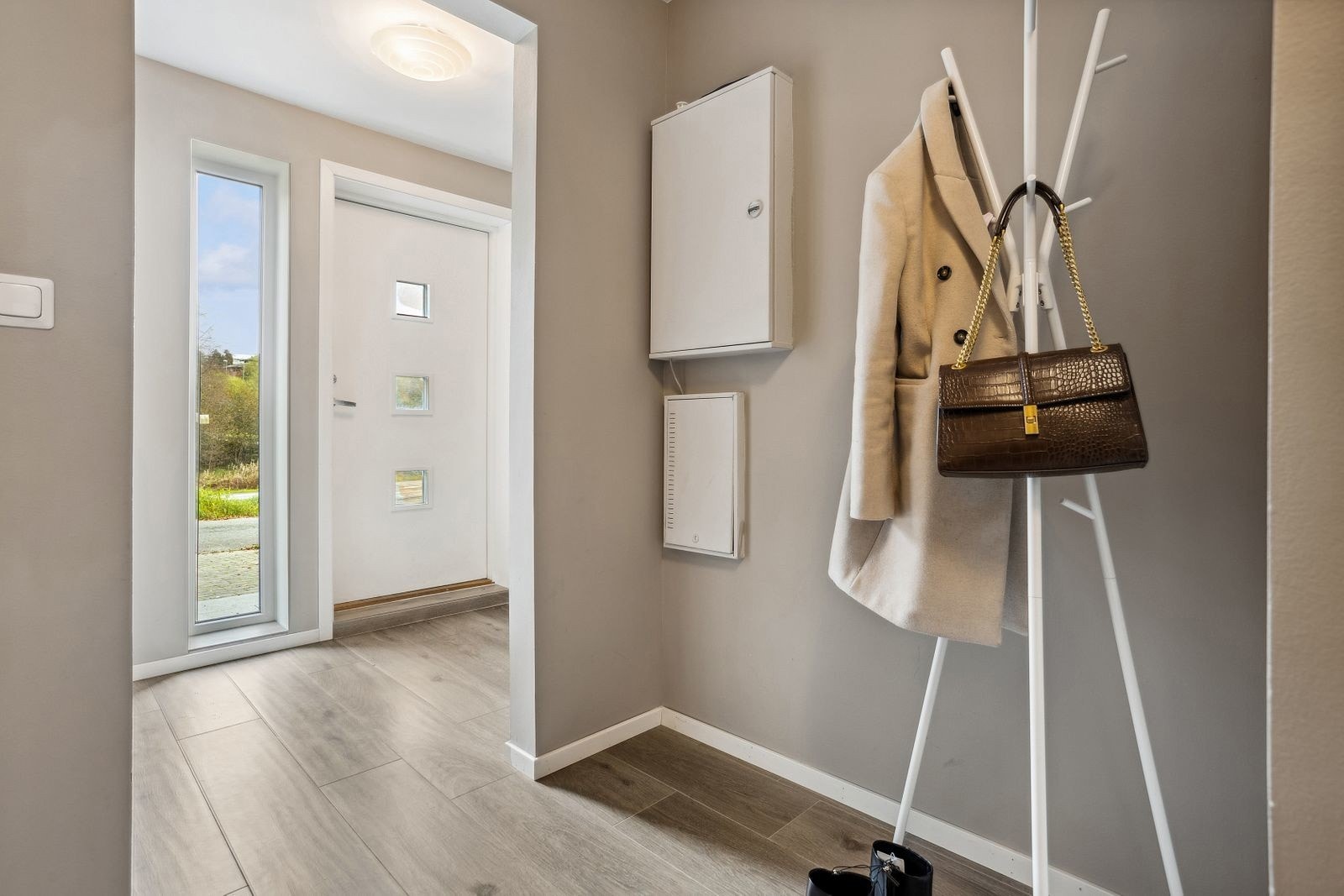 Lys og innbydende entré på 4,9 kvadratmeter med moderne garderobeløsning, samt en mellomgang på 6 kvadratmeter for ytterligere plass til oppbevaring av yttertøy og sko Galleribilde