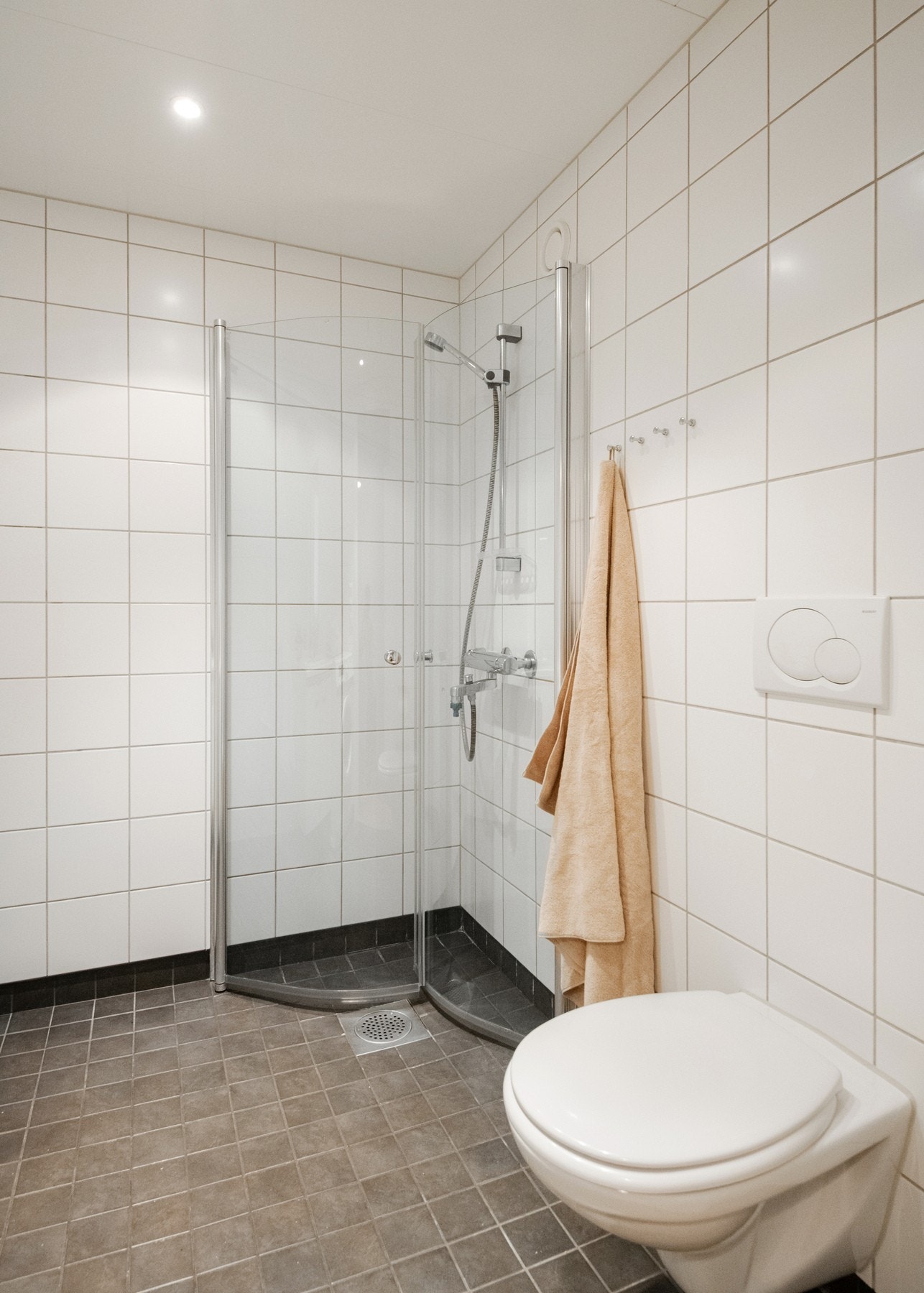 Badet er utstyrt med dusjhjørne med innfellbare dusjdører, toalett og servantinnredning. Galleribilde