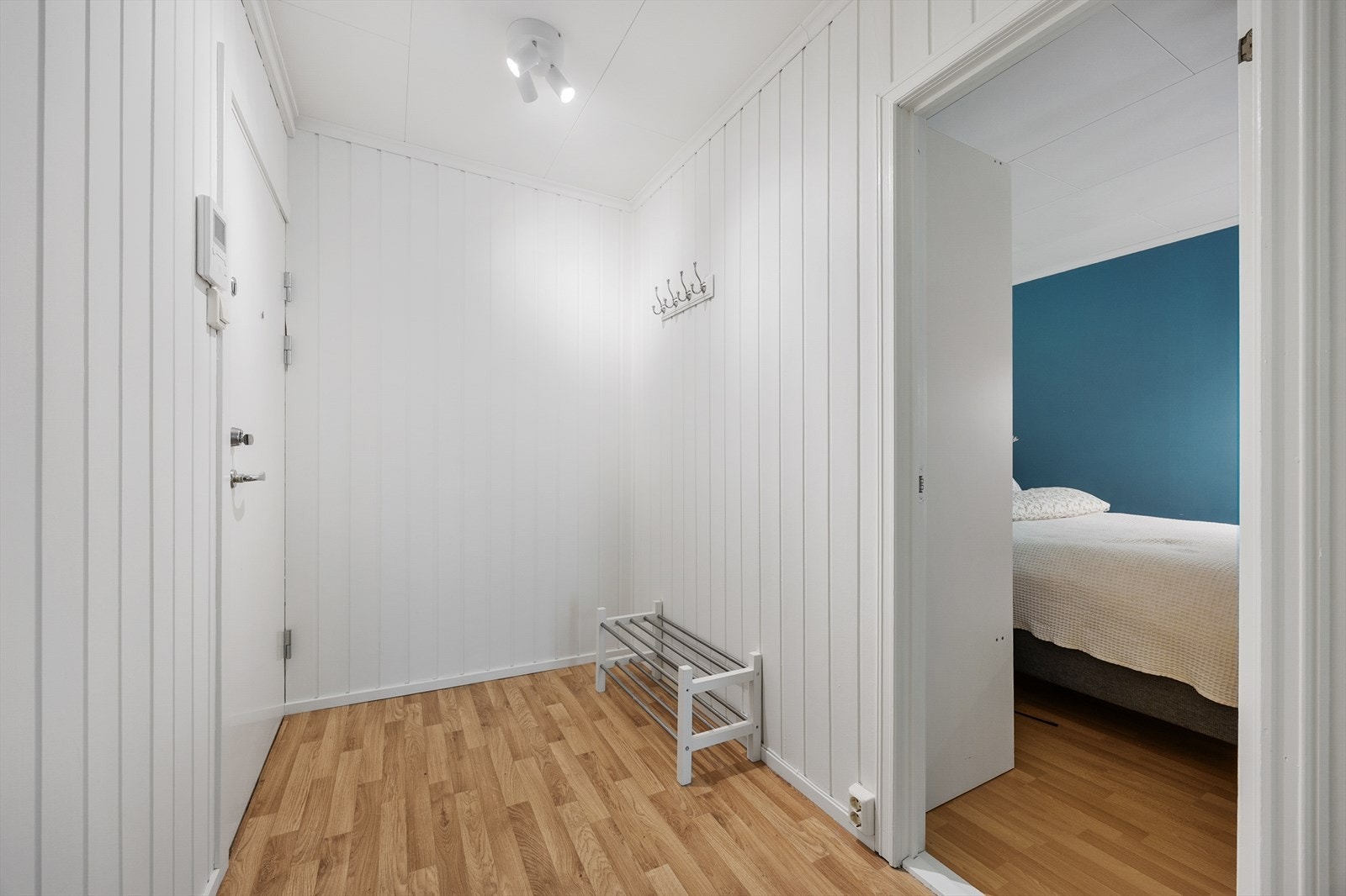 Romslig inngangsparti med god plass til oppbevaringsskap og knagger. Dørcalling på veggen. Galleribilde
