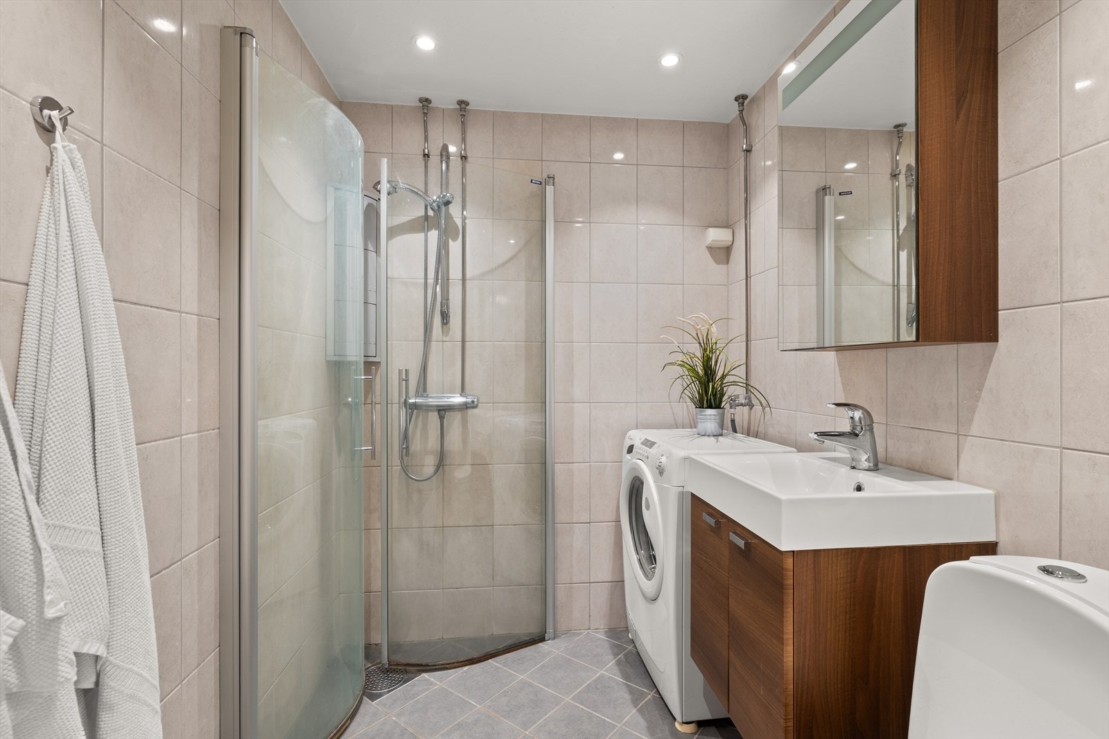 Pent flislagt baderom fra 2008 i regi av borettslaget. Badet har varmekabler i gulv, praktisk dusjhjørne, opplegg for vaskemaskin, toalett og servant med oppbevaring Galleribilde