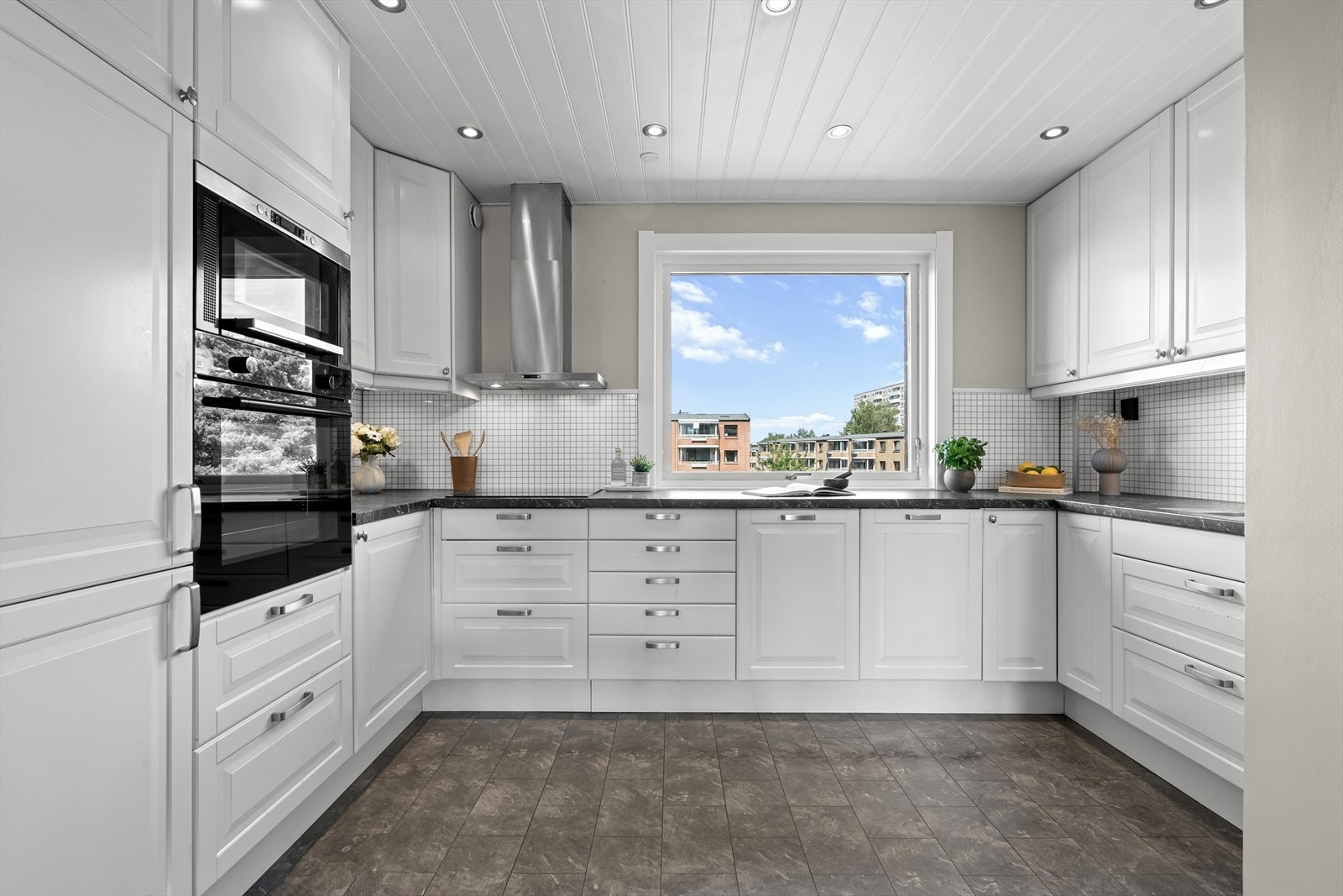 IKEA kjøkkeninnredning med lyse glatte fronter, benkeplate i laminat, integrerte hvitevarer med stekeovn, platetopp, mikro, oppvaskmaskin og kjøl/frys. Galleribilde