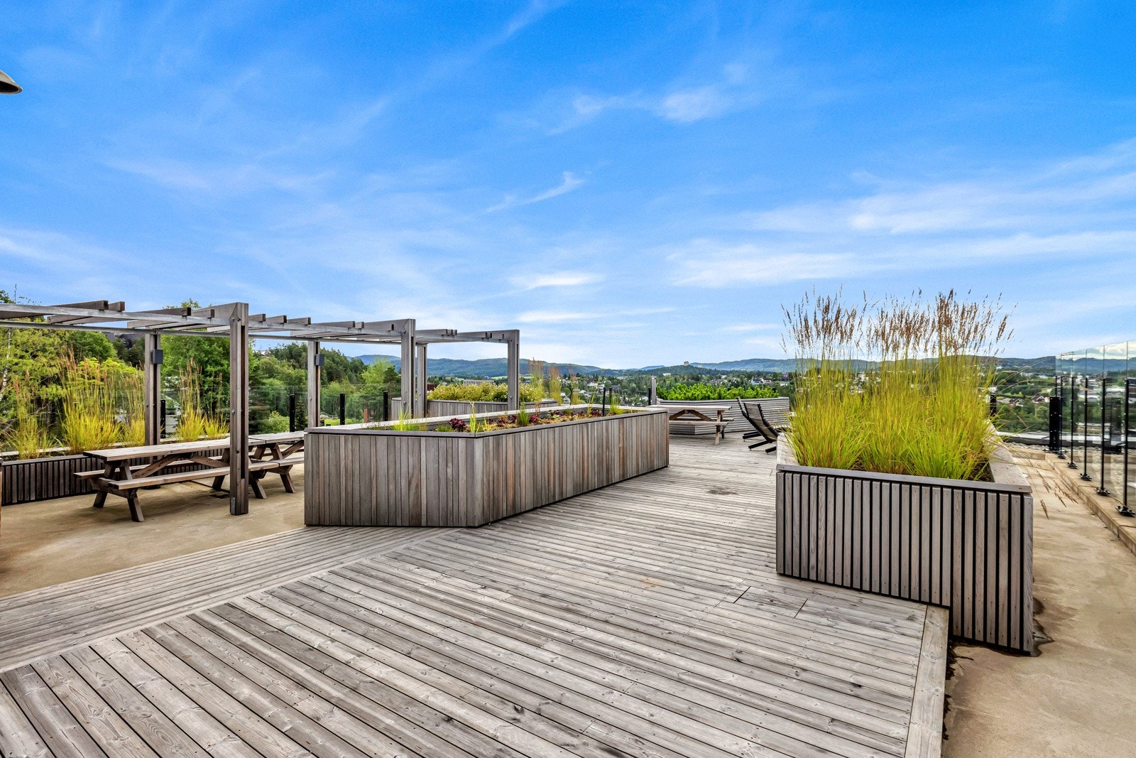 Grønn beplantning, blomsterkasser, pergola og solsenger for å nevne noe. Galleribilde