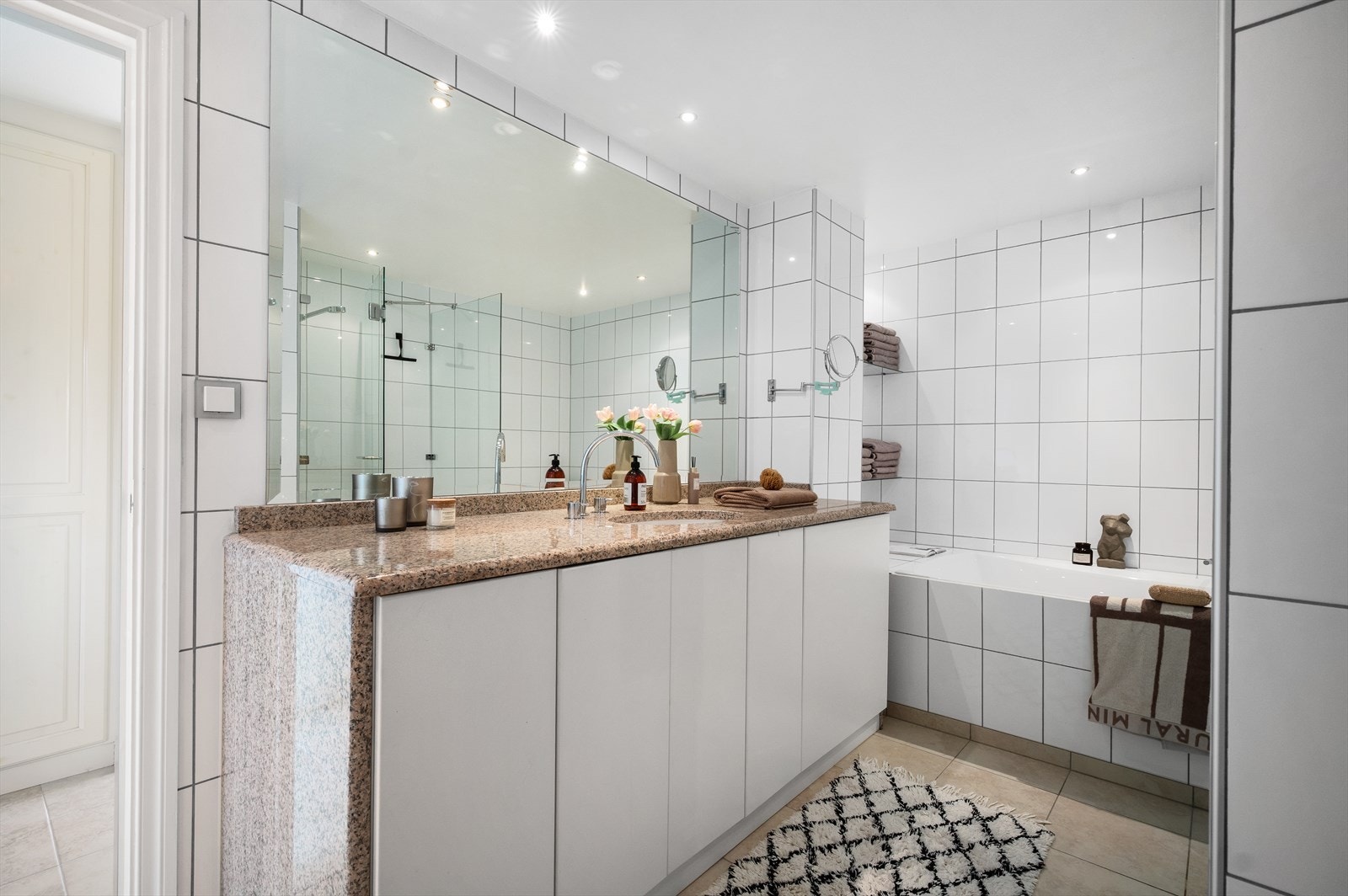 Badet er utstyrt med badekar, servantmøbler med steinplate, dusjhjørne og vegghengt toalett. Galleribilde