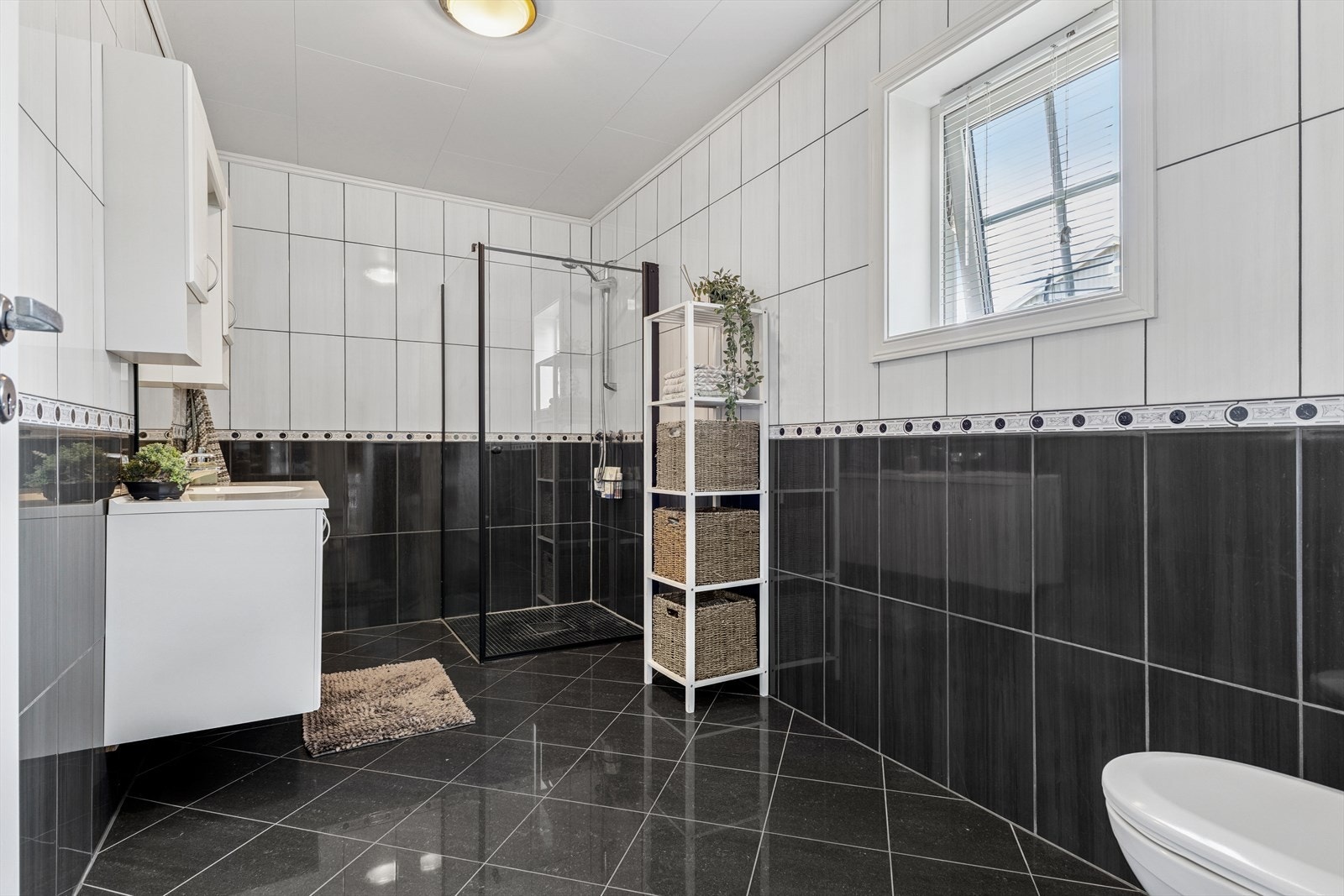 Badet er ellers utstyrt med dusjhjørne, vegghengt toalett og veggseksjon med servant. Galleribilde