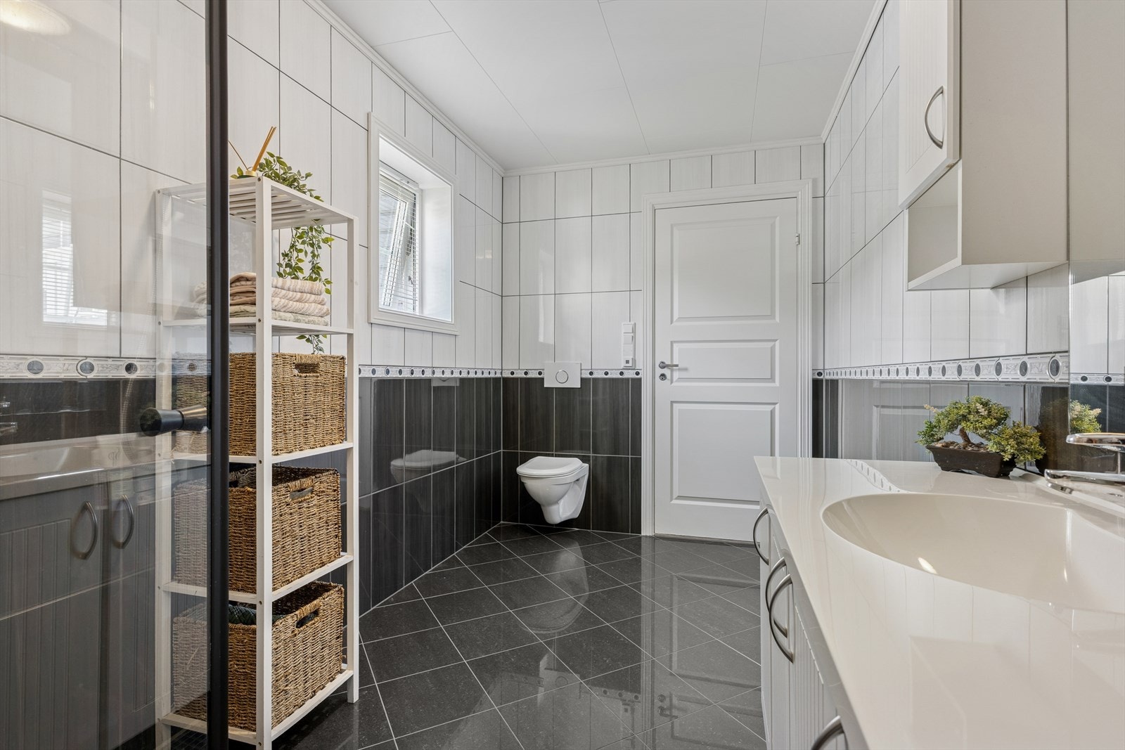 Baderommet i første etasje ble modernisert i 2024 med egeninnsats og er innredet med en kombinasjon av grå og hvite fliser på gulv og vegger. I gulvet har man også varmekabler for ekstra komfort. Galleribilde