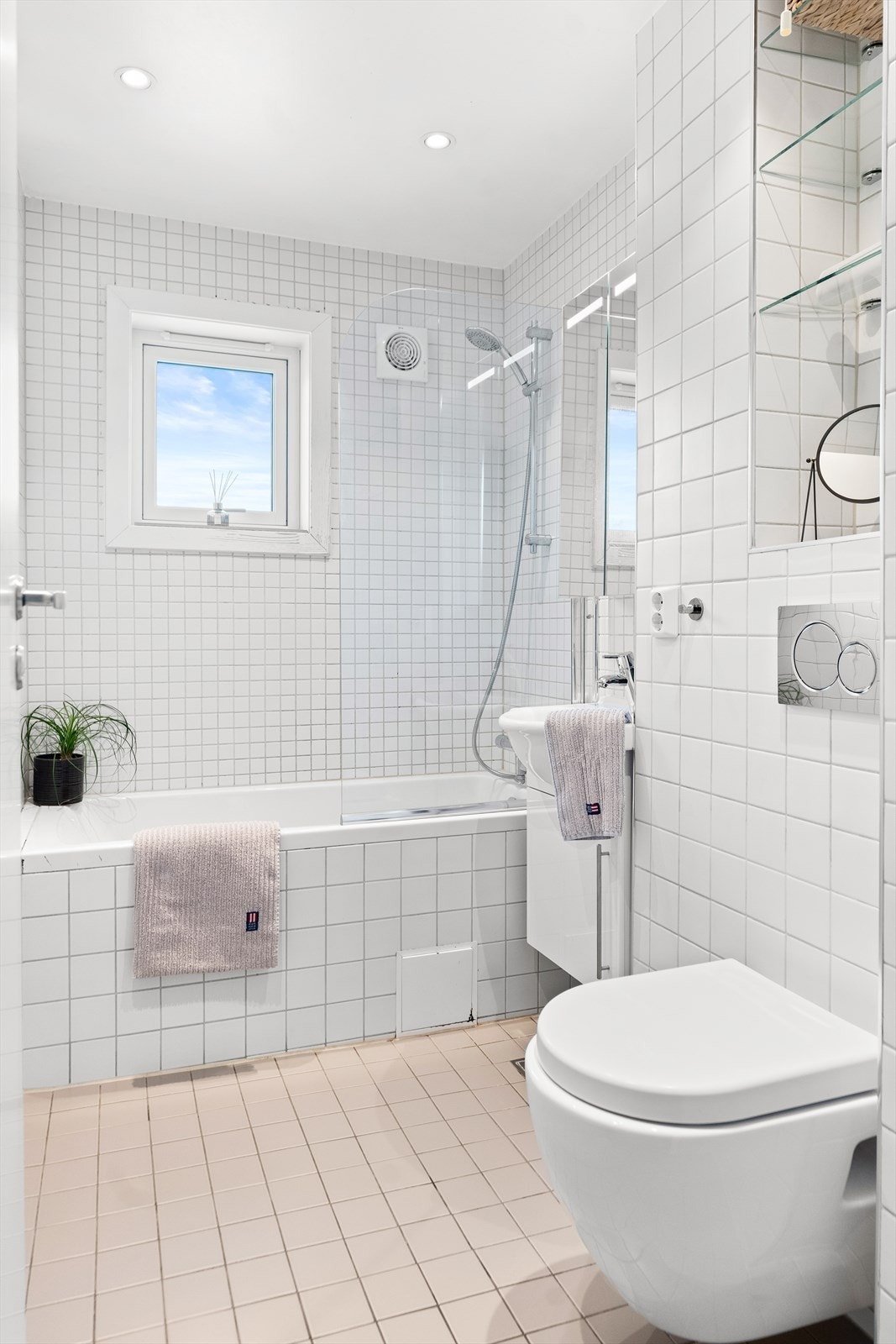 Videre har badet vegghengt toalett og dusjnisje med glassdører Galleribilde