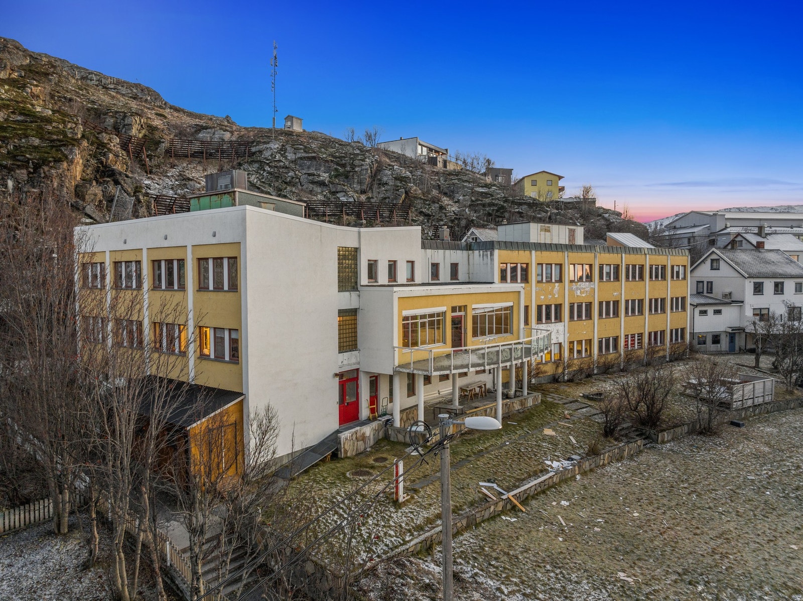 Fasade utvendig. Området rundt er spredt boligbebyggelse. Galleribilde