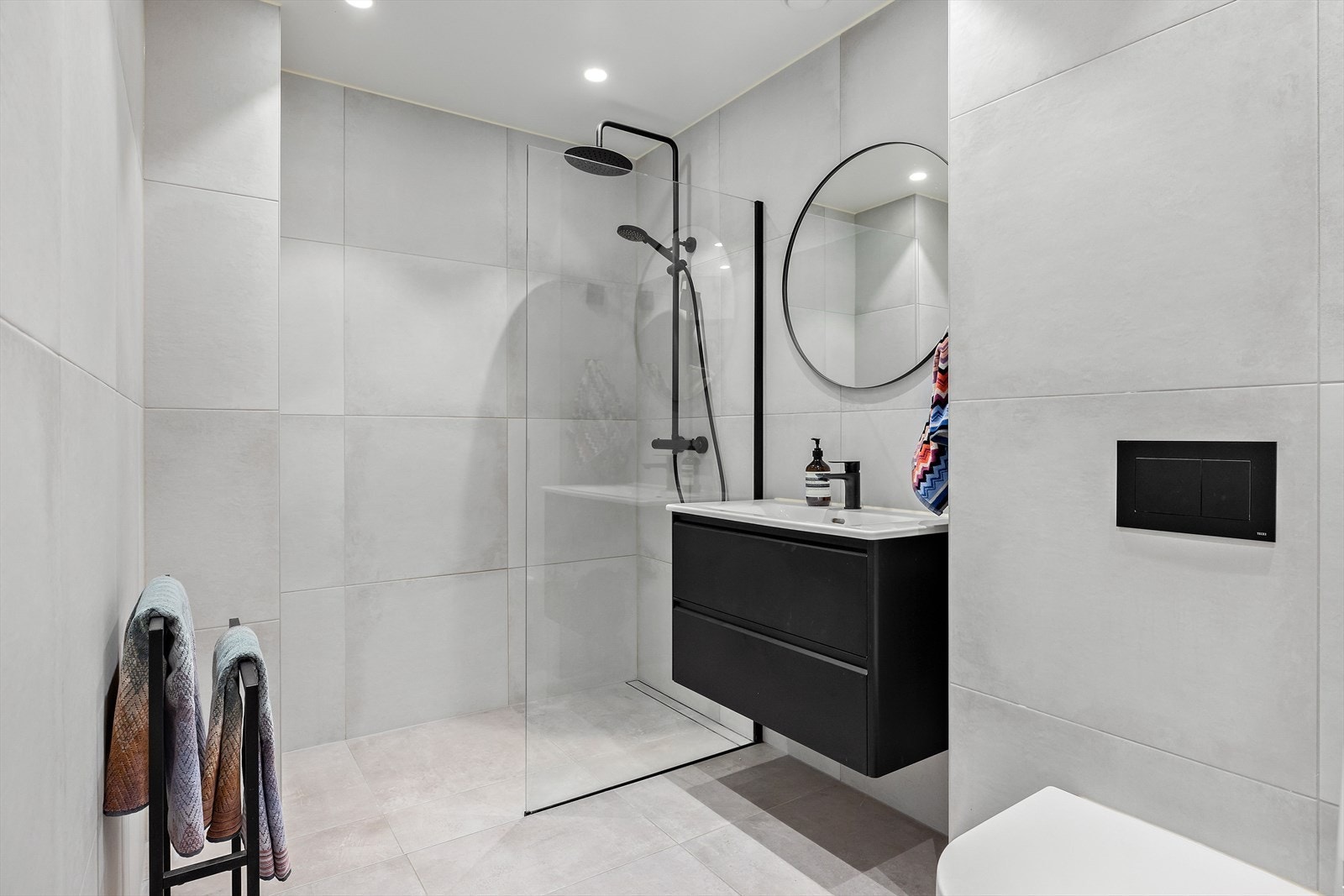 Delikat baderom fra 2021 med påkostede detaljer som blant annet regnfallsdusj og rennesluk. Rett utenfor badet er det også et praktisk, plassbygget skap. Galleribilde