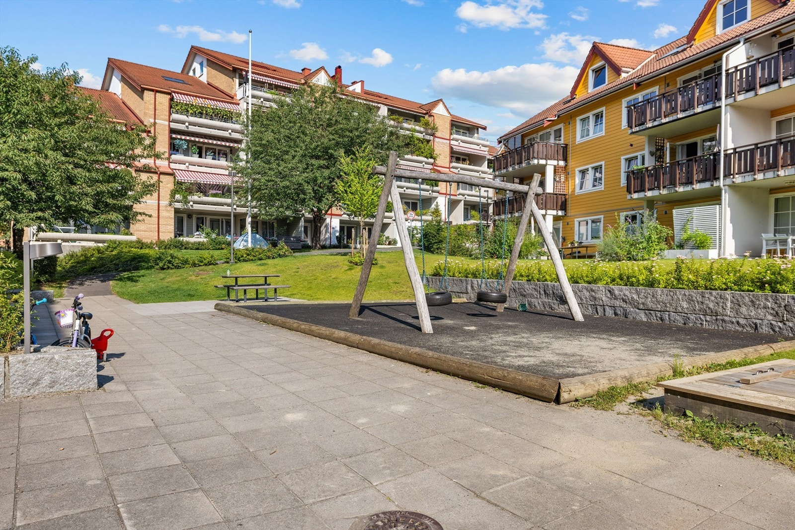 Eiet tomt med skjermet bakgård, beplantet med blomster og trær - fellesområdet er til glede for beboerne Galleribilde