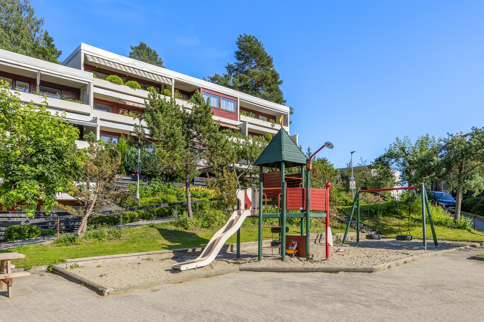 Leiligheten og terrassen ligger skjermet fra lekeplassen med busker og trær uten at de skygger for solen. Galleribilde