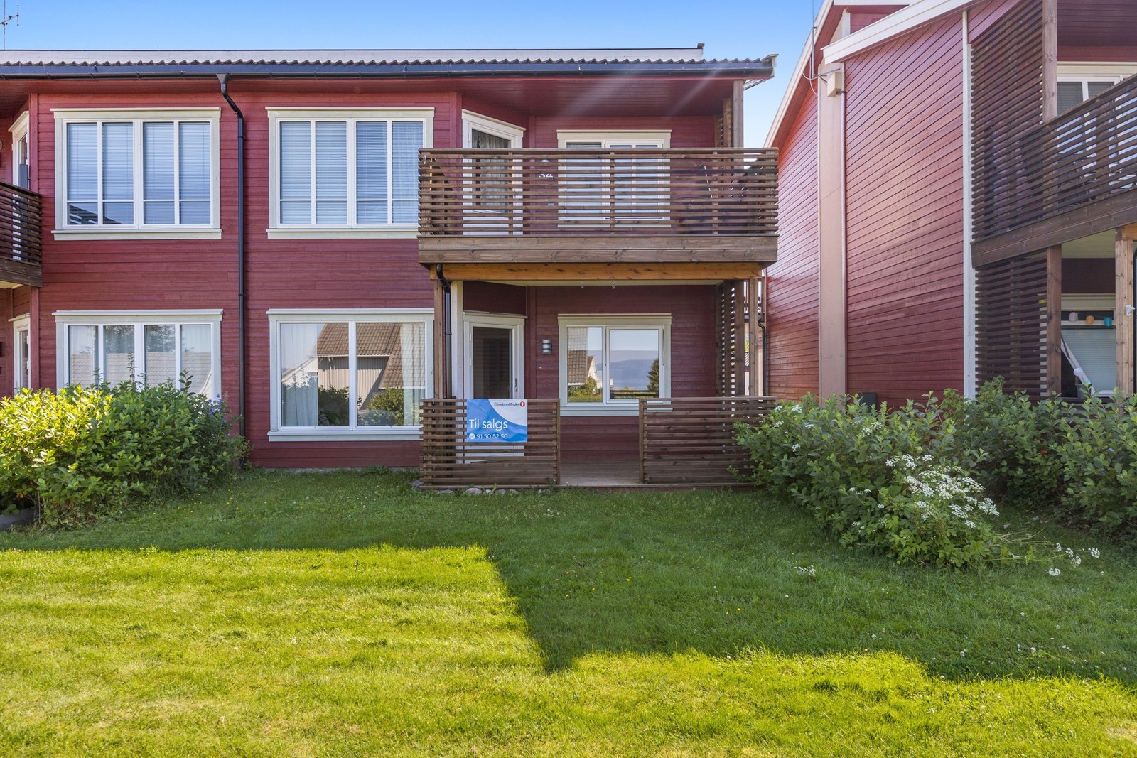 Plenlagt fellesareal som er beplantet med busker og bed. Galleribilde