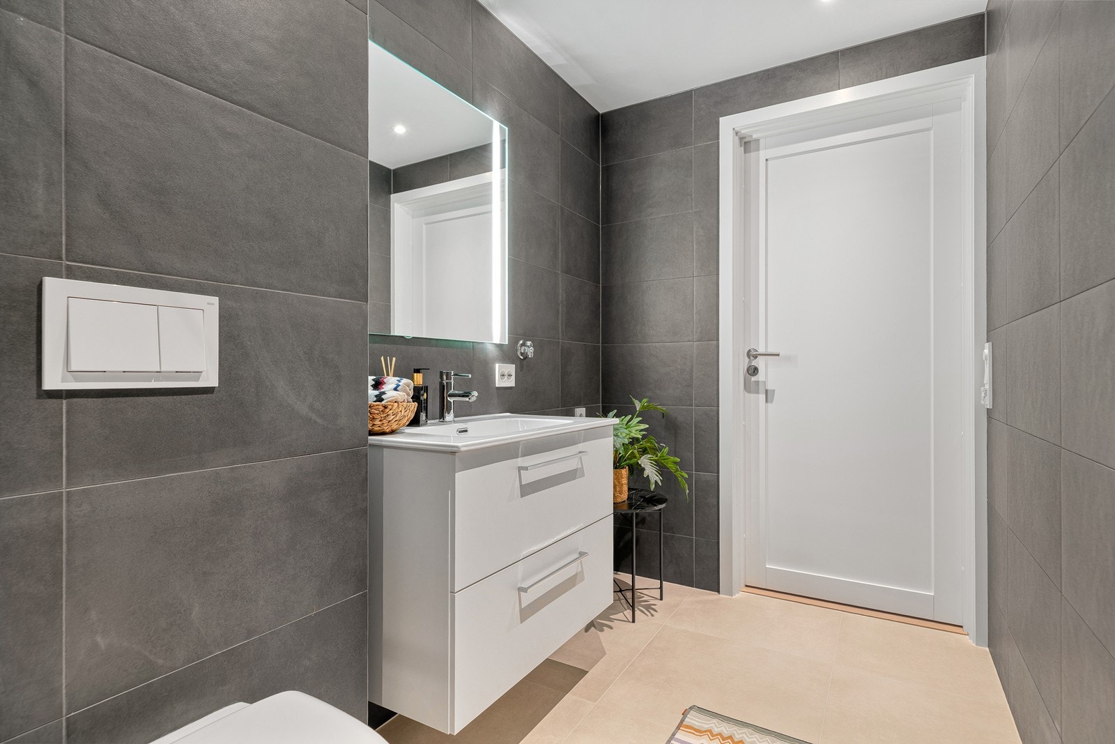 Badet er innredet med nedfelt servant, vegghengt toalett og dusjhjørne med innfellbar dør Galleribilde