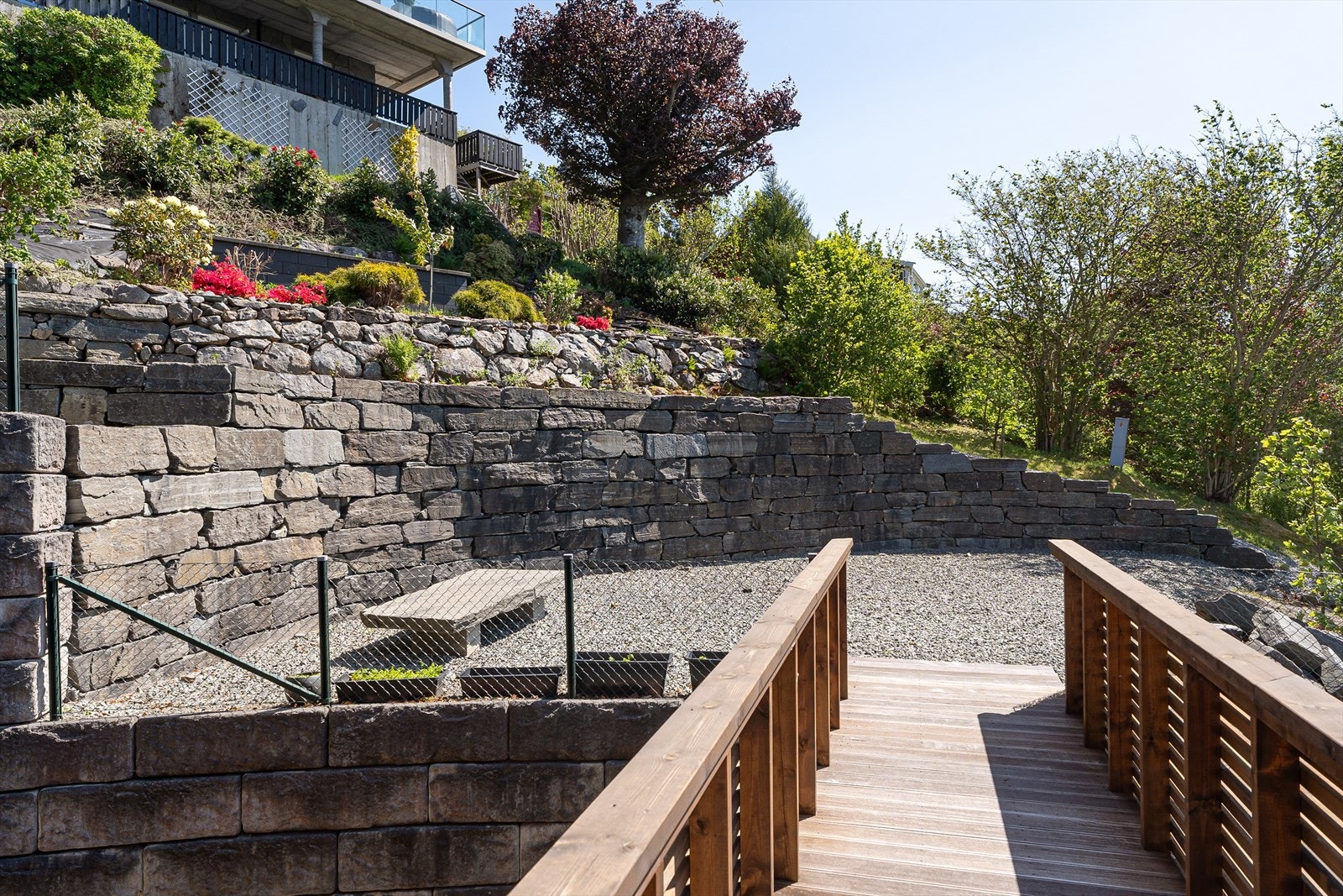 Det er satt opp fin gangbro fra terrassen i hovedetasjen over til bakkenivå og tiltenkt område for terrasse/uteområde (laget i 2024) Galleribilde