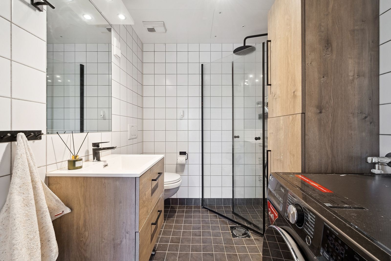 Flislagt bad med wc, servant, dusjhjørne og kombinert vaskemaskin og tørketrommel Galleribilde