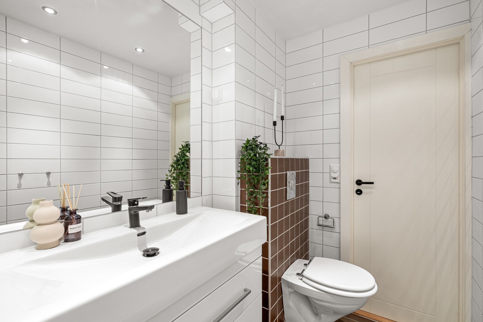 Det er et vegghengt toalett, vegghengt baderomsmøbel med vask, opplegg til vaskemaskin samt et dusjkabinett Galleribilde