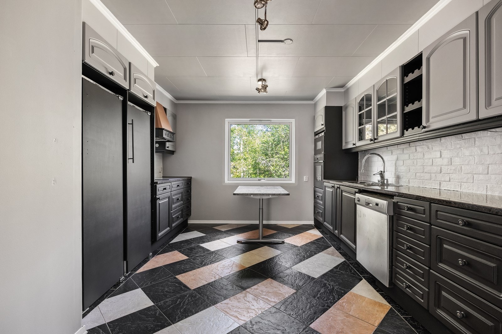 Kjøkkeet er innredet med skap med mørke profilterte fronter og benkeplate i stein. Galleribilde