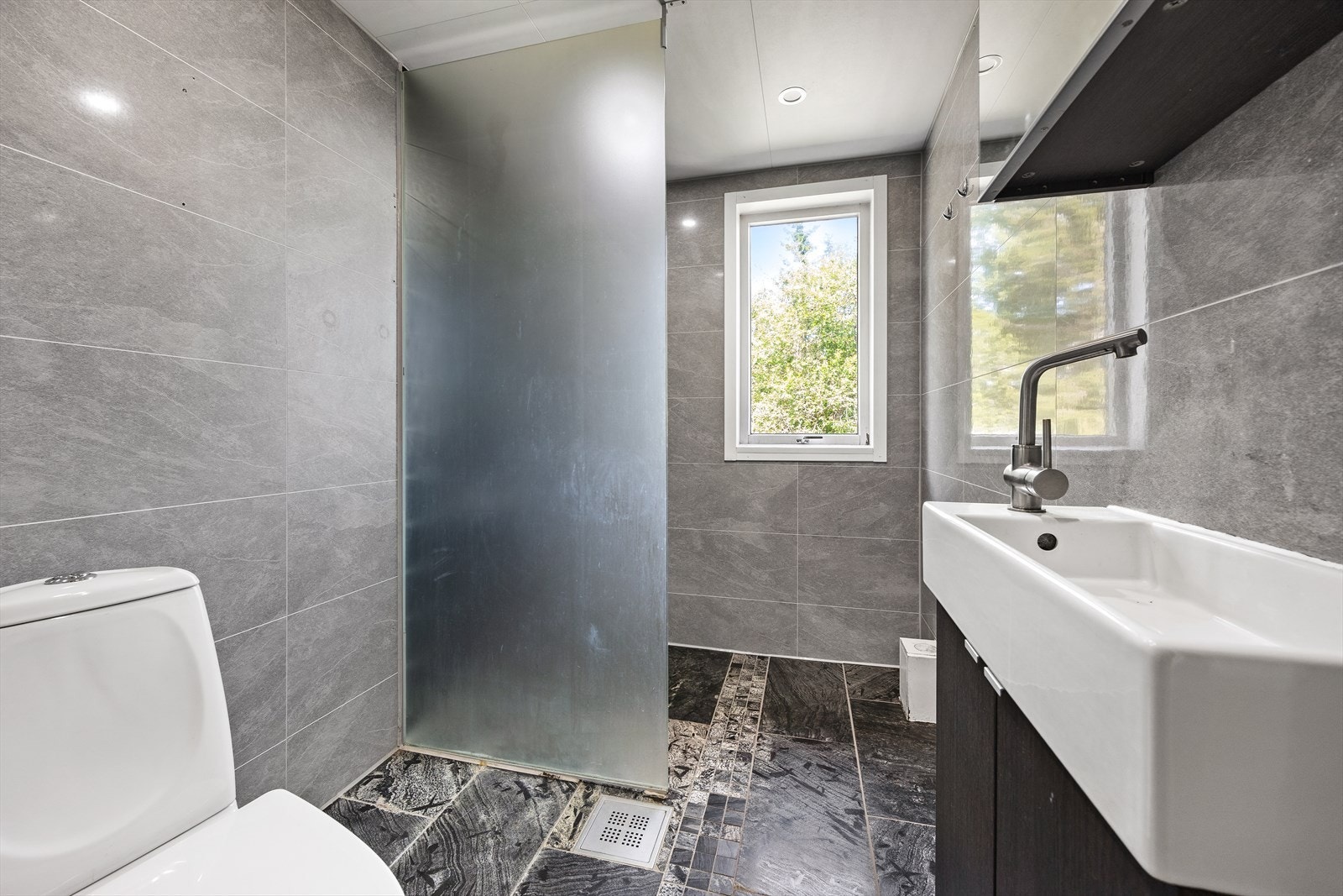 Badet er av god størrelse med fliser på vegger og gulv. Galleribilde