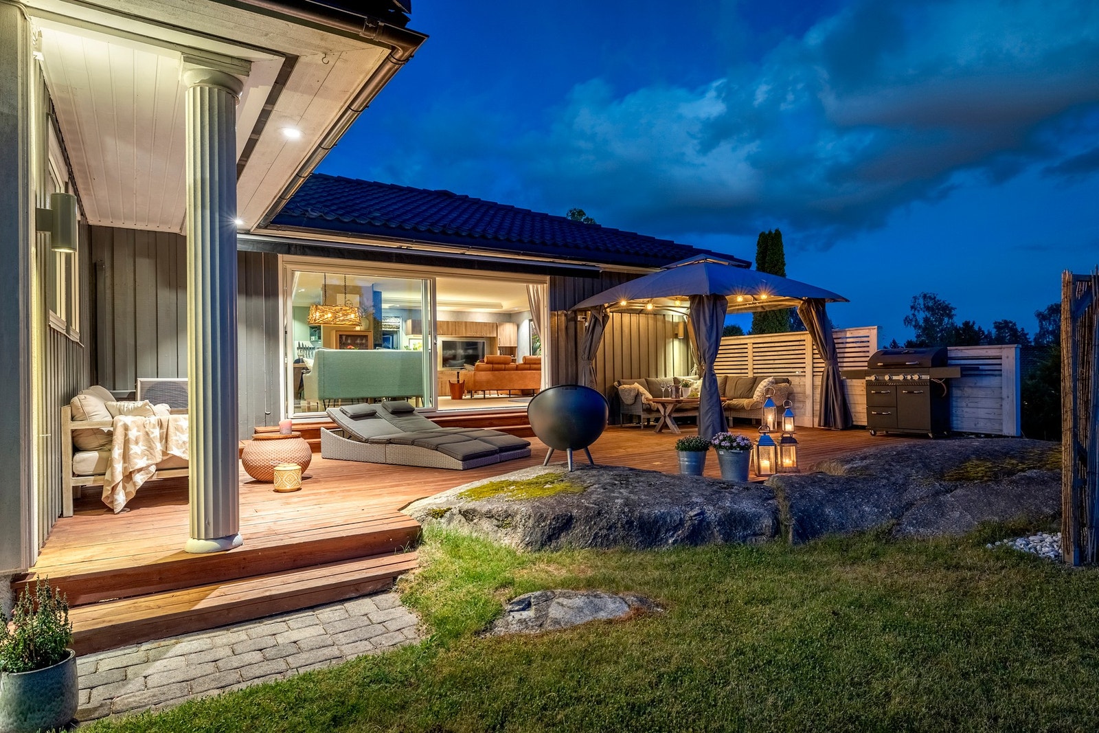 Den store, solrike terrassen mot sydvest er bygd helt inntil fjellknauser i hagen og har noe overbygg med downlights. Det er levegg langs sydsiden og god plass til flere komfortable utemøbler, grill og paviljongtelt. Fjellknausen er ellers et perfekt sted Galleribilde