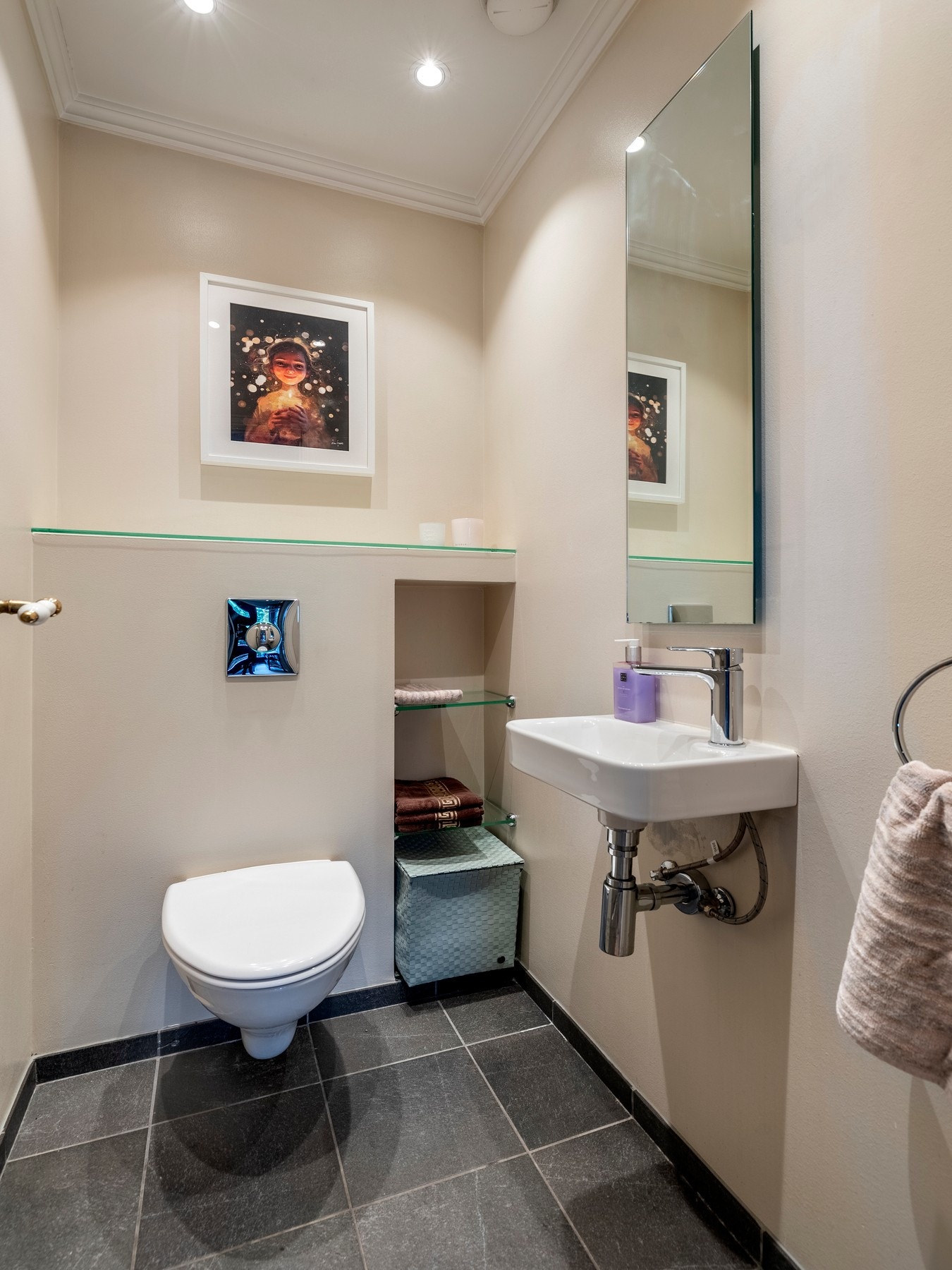 Toalettrommet i første etasjen har adkomst fra gangen, og er innredet med veggmontert toalett, servant, speil, vegghyller, downlights, glatte veggflater og flislagt gulv. Galleribilde