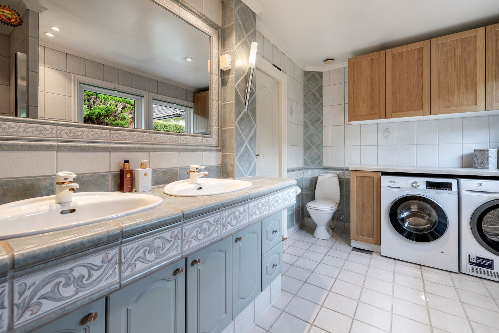 Boligen har to bad og to toalettrom, ett av hver i begge etasjer. Badet i første etasje er av eldre dato med flislagte vegger og gulv, gulvvarme, downlights og to nordvendte vinduer mot skjermet uteareal. Rommet er innredet med dobbelservant nedfelt i fli Galleribilde