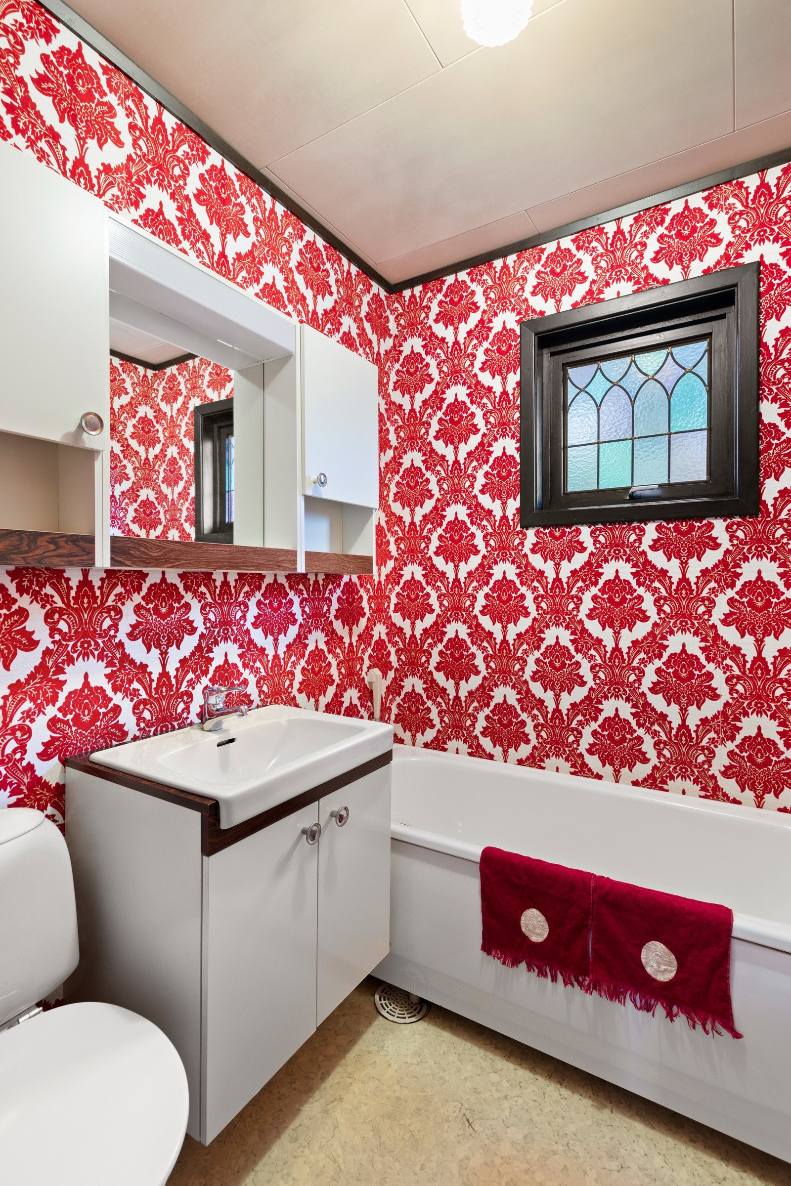 Badet i etasjen er fra byggeår og har belegg på gulv og tapet på vegger. Rommet har varmekabler i gulv, badekar, toalett og vegghengt servant. Galleribilde