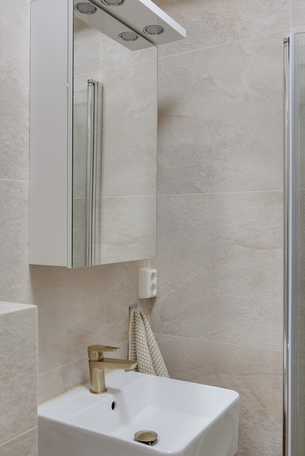 Badet er innredet med servant nedfelt i stilren innredning, speilskap med integrert belysning. Galleribilde