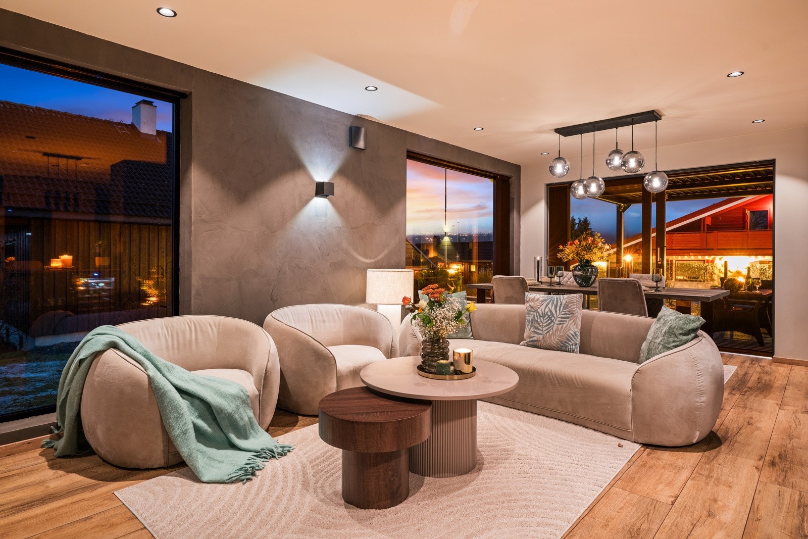 Stuen forvandles til en lun og innbydende atmosfære på kveldstid, med stemningsfull belysning og store vindusflater som slipper inn det siste dagslyset Galleribilde