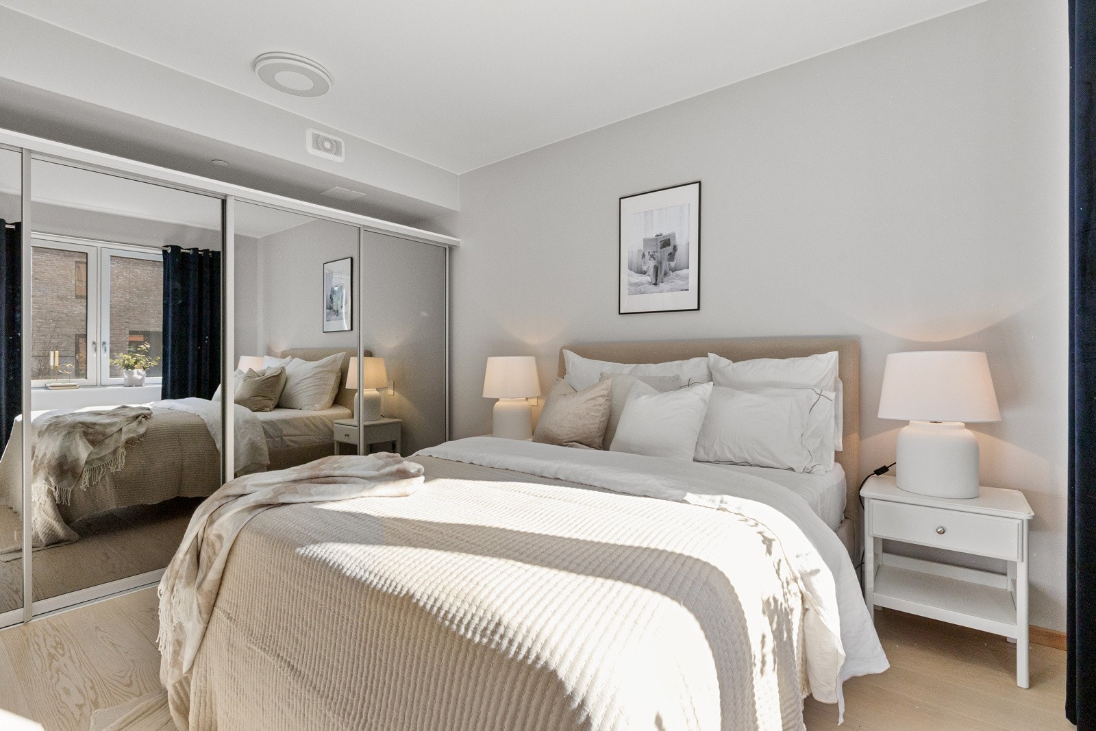 soverommet innredet med en stor skyvedørsgarderobe med speilfronter som gir praktisk oppbevaringsplass for klær og sengetøy Galleribilde