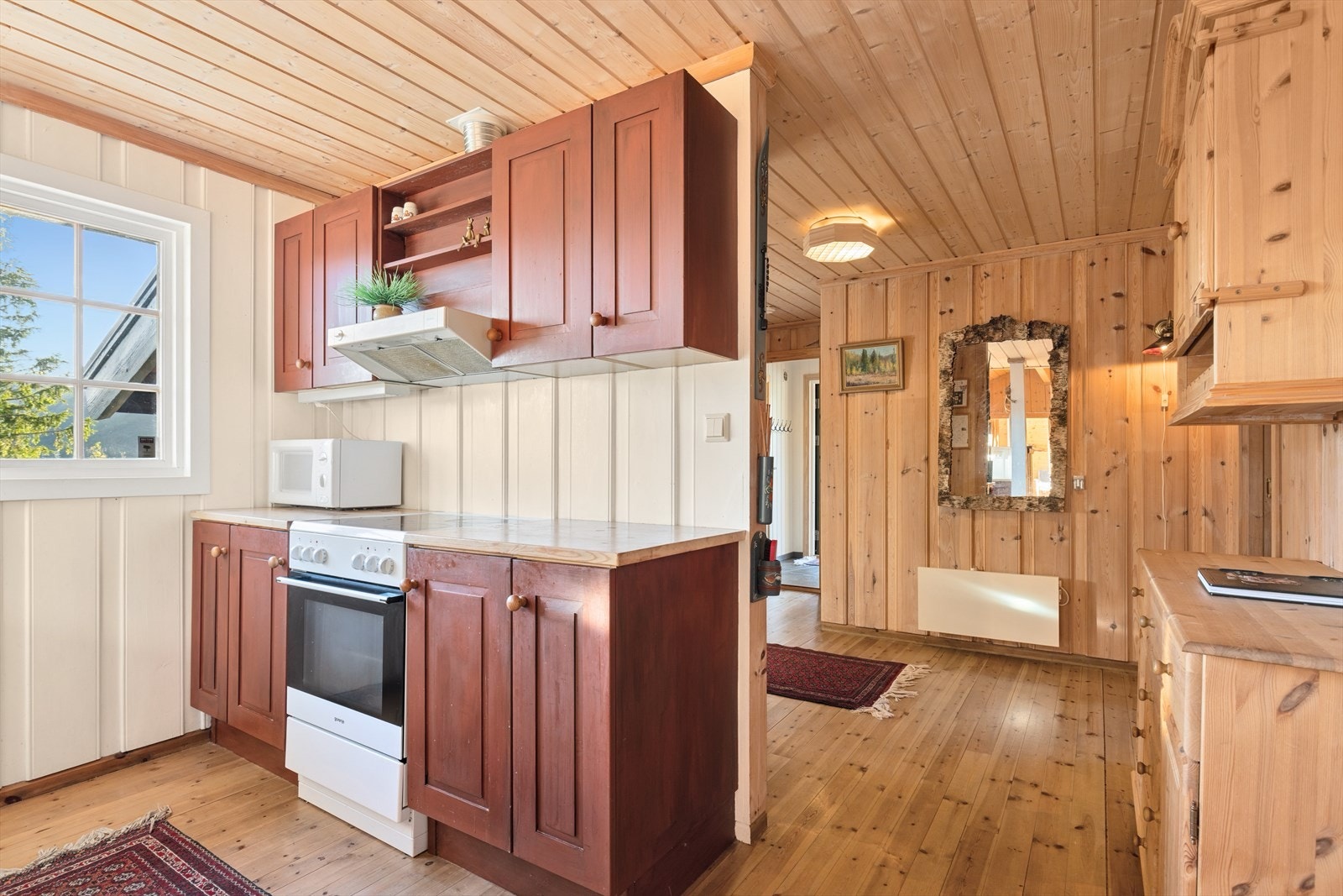 Delikat hyttekjøkken med malte og profilerte fronter og heltre benkeplate med oppvaskkum. Galleribilde