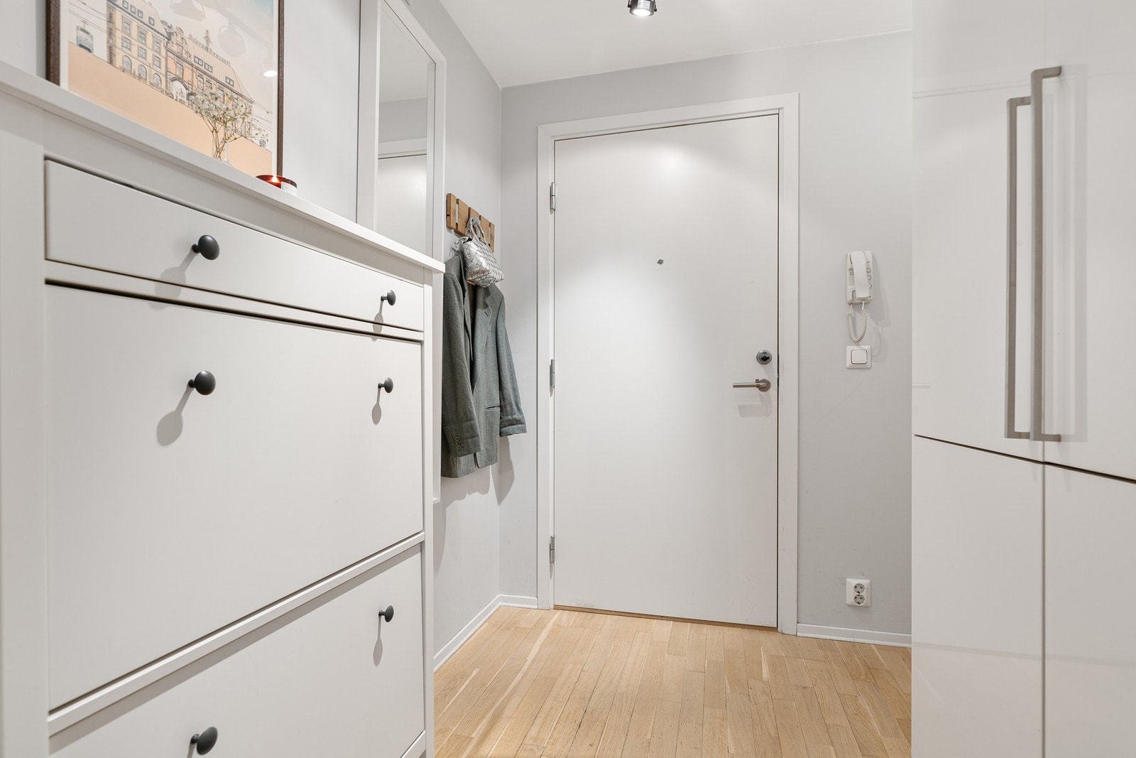 Man ankommer en romslig entré som er innredet med garderobeskap og som har ytterligere plass til annet entrémøblement. Galleribilde