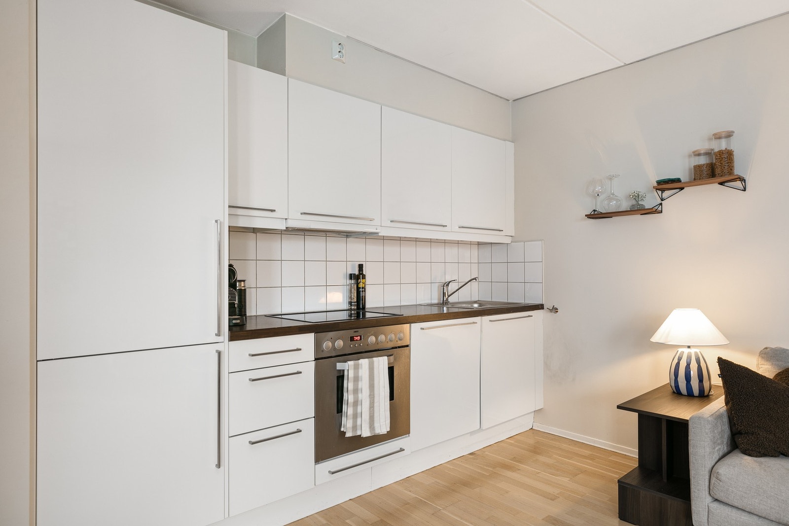 Kjøkkeninnredningen er med hvit, glatt innredning og benkeplate i en mørkfarget laminat med oppvaskkum. Galleribilde