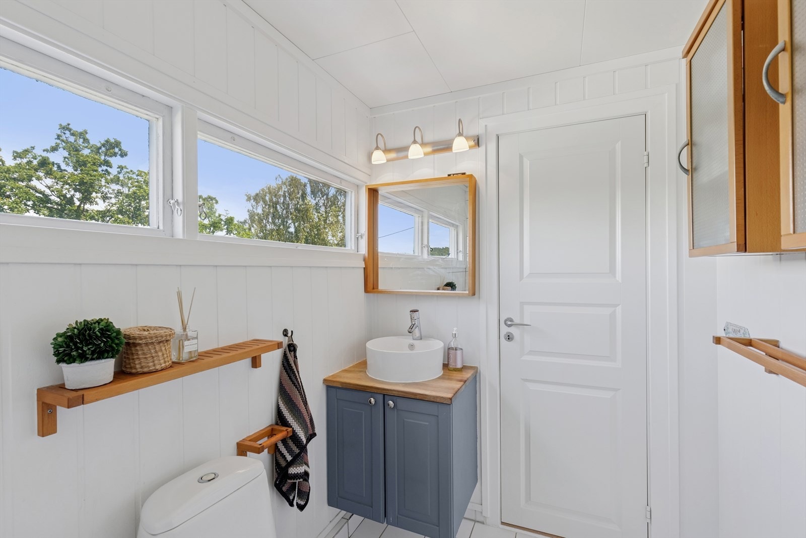 Badet er innredet med servant med skap, gulvstående toalett og badekar. Galleribilde