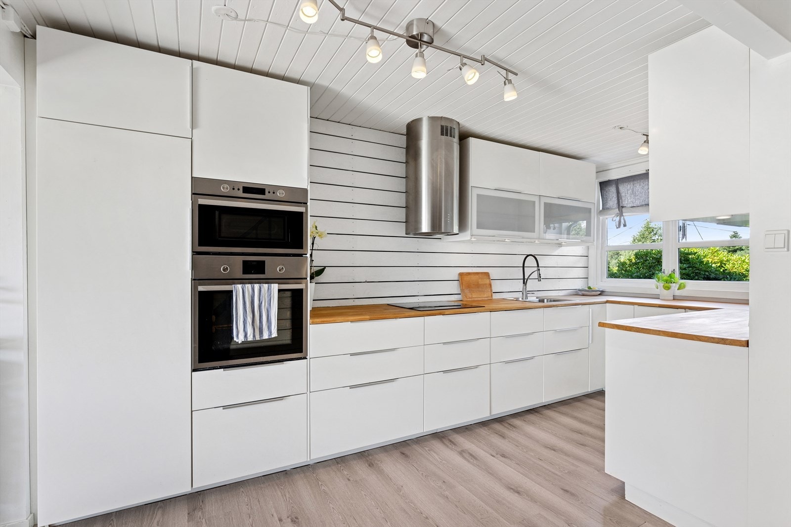 Delikat kjøkken med lyse, slette fronter og heltre benkeplate med oppvaskkum. Galleribilde