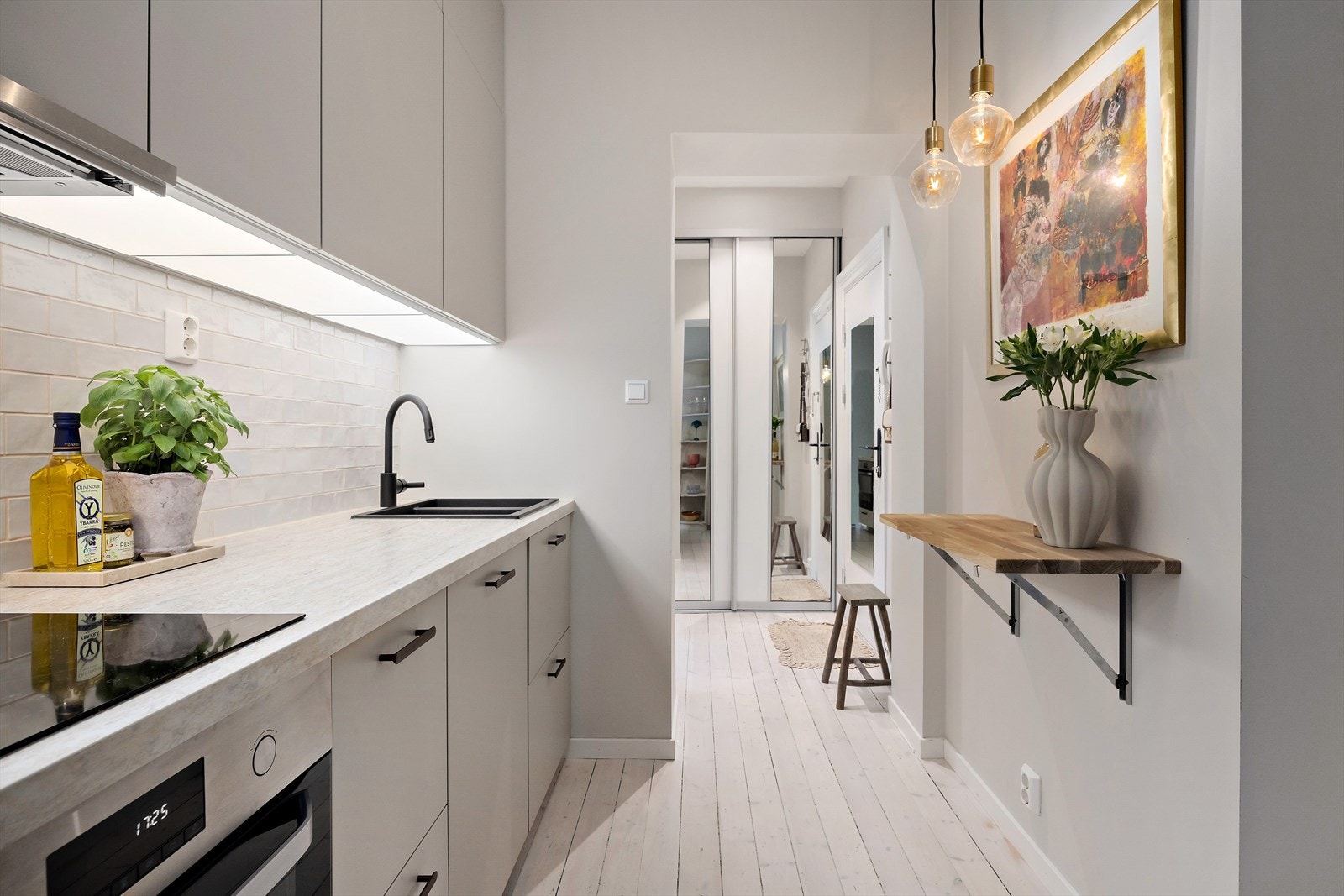 Lekkert kjøkken med lyse fronter, svarte detaljer og rikelig med skapplass - et stilrent og funksjonelt samlingspunkt i boligen. Galleribilde