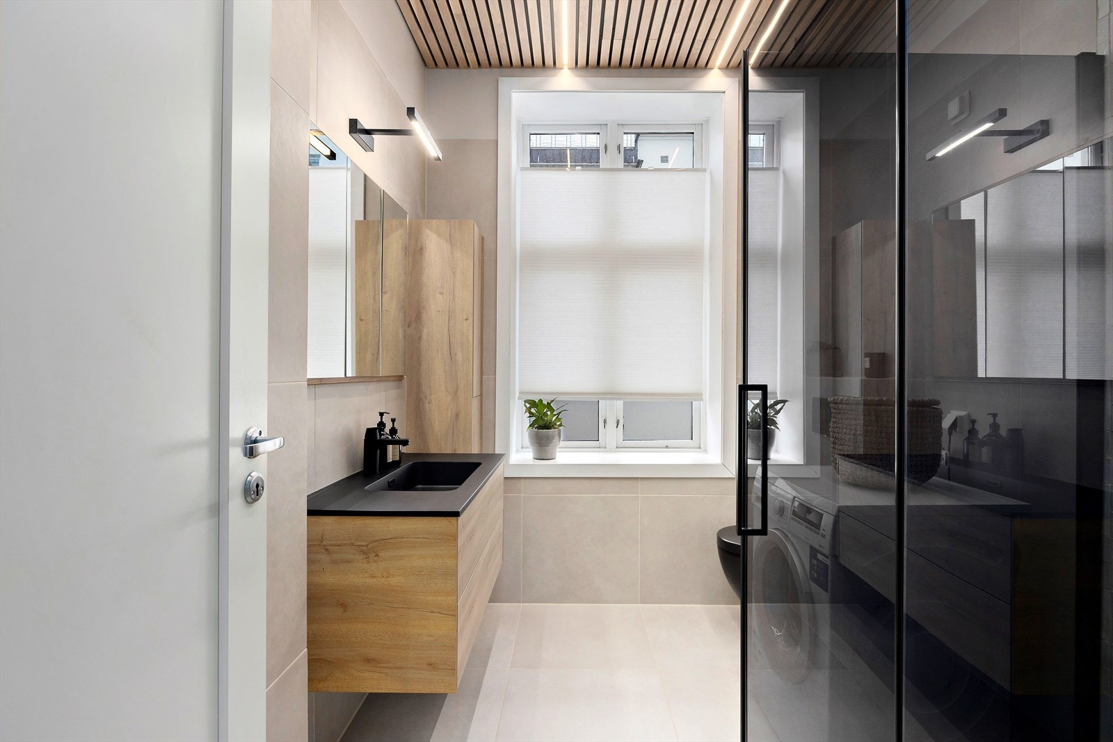 Delikat bad fra 2023 med dusjhjørne, varmekabler og opplegg for vaskemaskin. Galleribilde