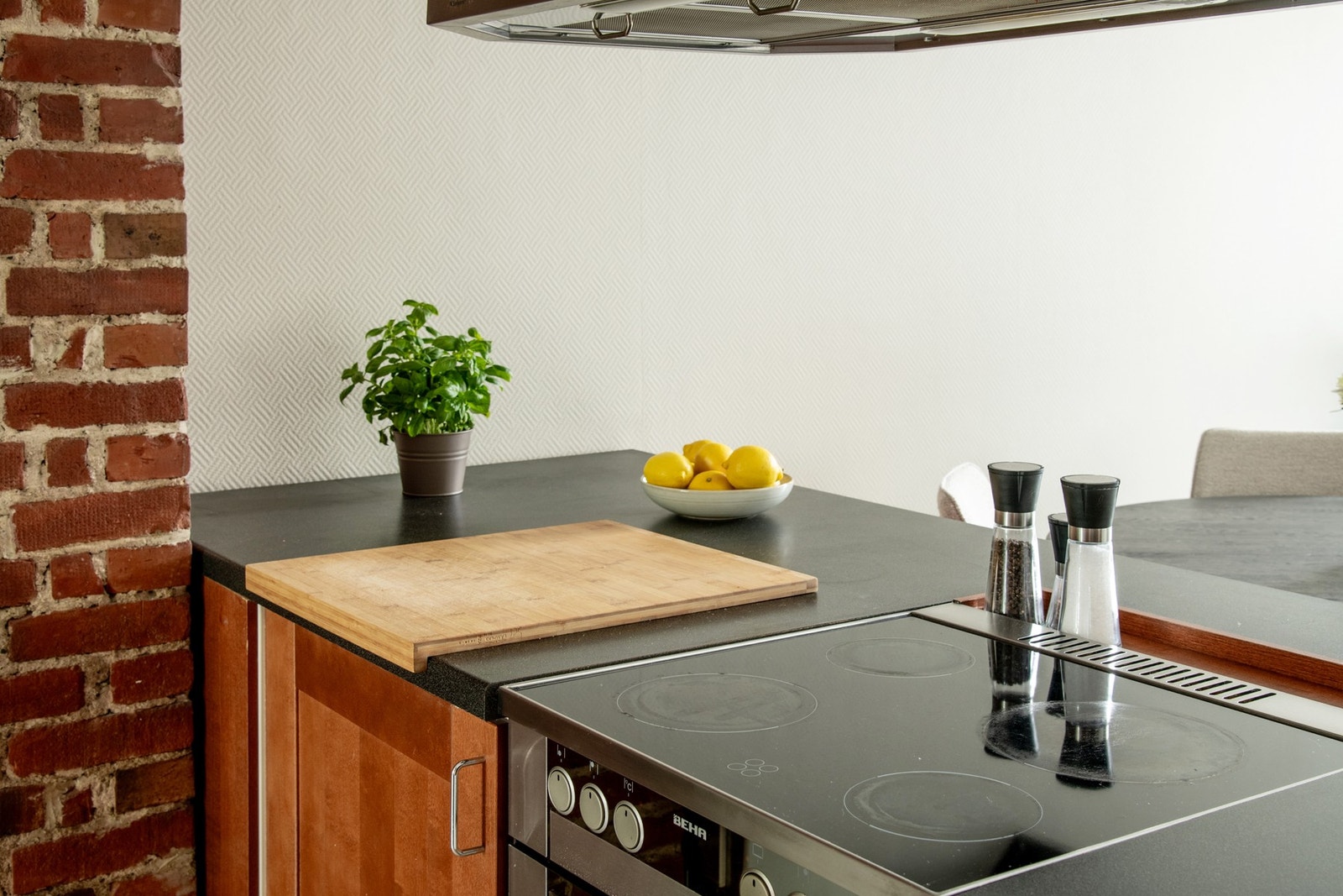 En stor kjøkkenøy med platetopp skaper en naturlig og funksjonell sone mellom stue og kjøkken. Galleribilde