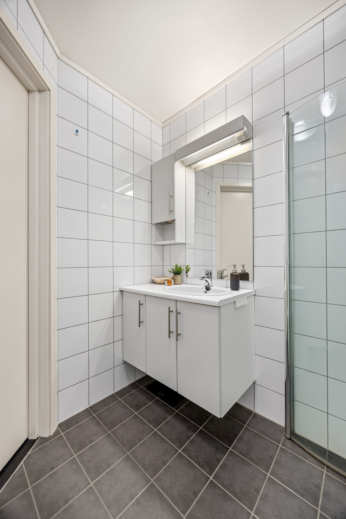 Badet er utstyrt med bl.a. gulvvarme, dusjhjørne, veggmontert WC, servantskap og opplegg for vaskemaskin. Galleribilde