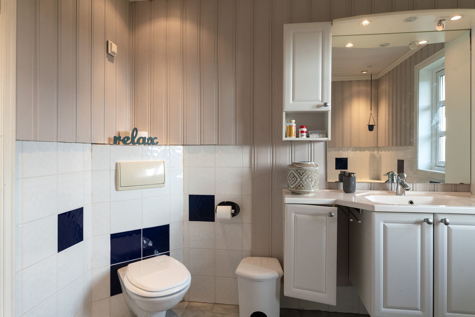 Badet har innredning med skap, servant, speil og belysning. Veggmontert toalett. Galleribilde