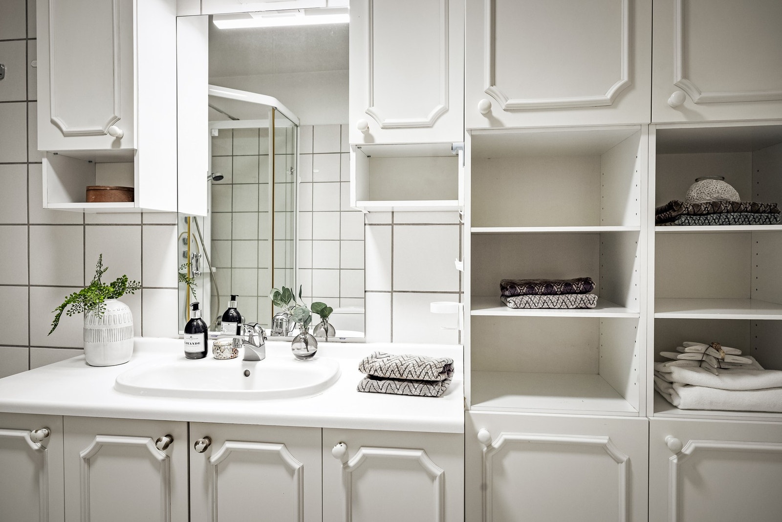 Baderomsinnredning med hvite fronter og servant med ett-greps blandebatteri. Galleribilde