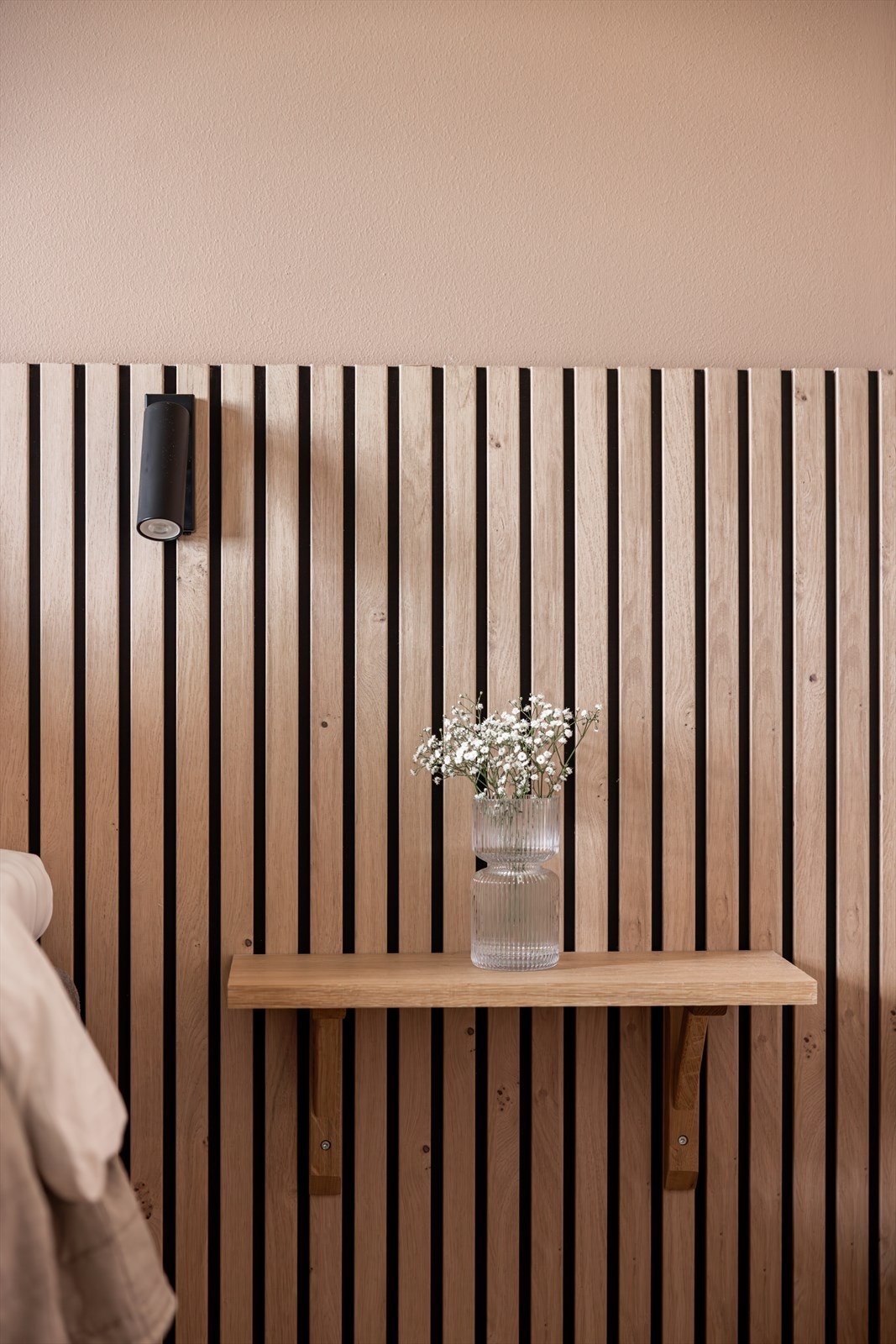 Plassbygde nattbord og en stilig spilevegg bak sengen gir rommet karakter og en lun atmosfære Galleribilde