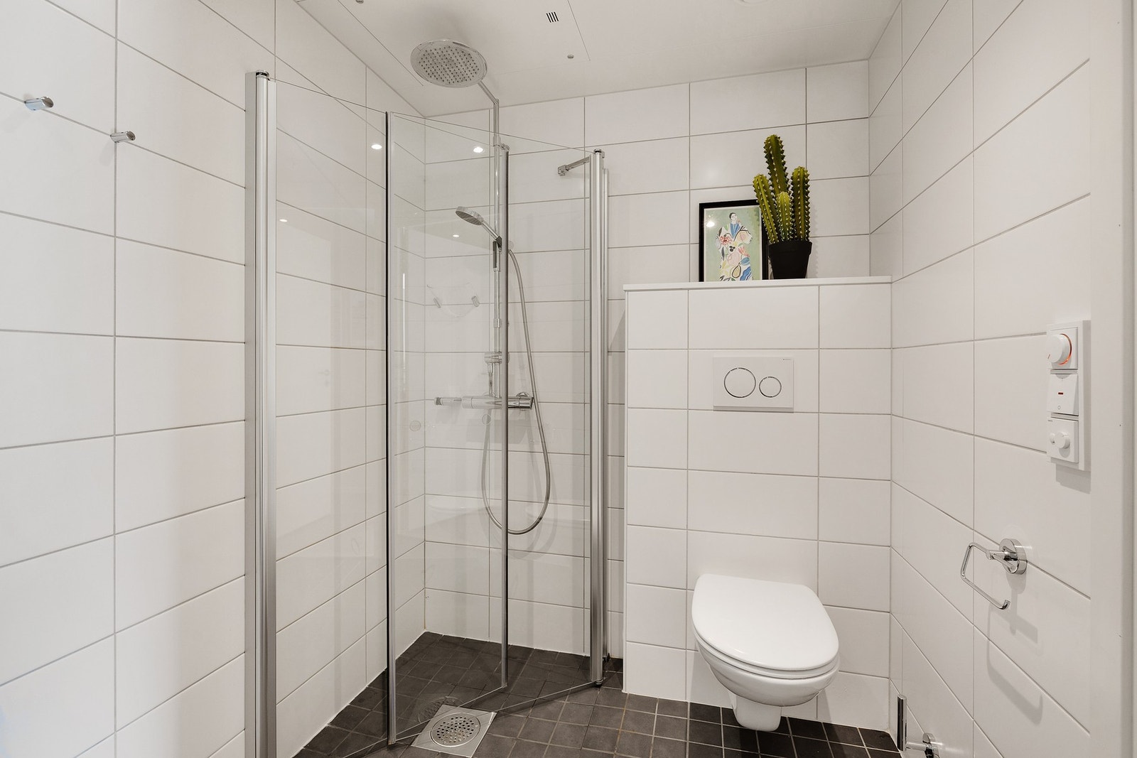 Badet er innredet med vegghengt toalett, vegghengte dusjdører i glass, samt moderne baderomsinnredning Galleribilde