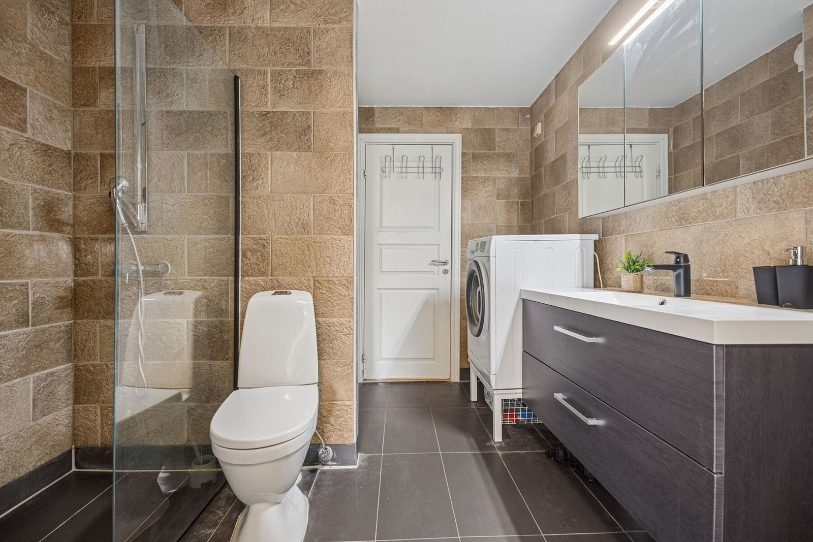 Badet er innredet med veggmontert dusjvegg og dusj direkte på gulv med termostatstyrt batteri. Galleribilde