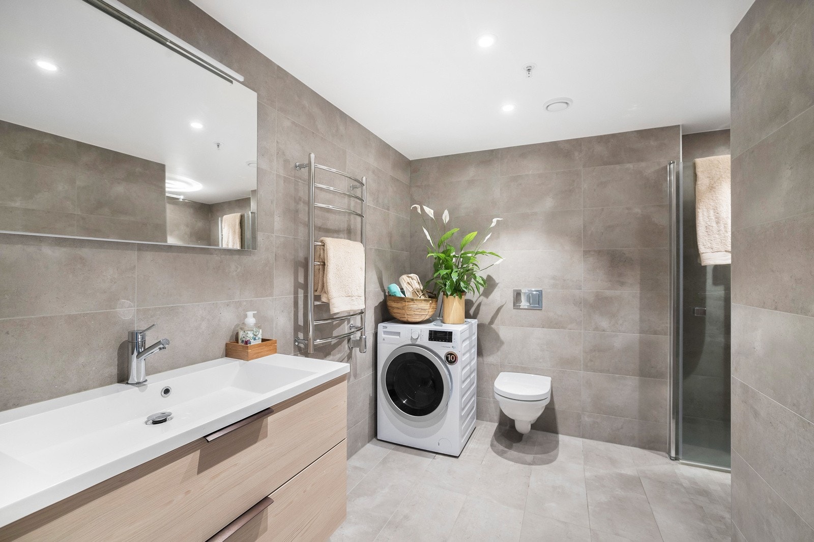 Badet er delikat med store fliser på overflater, downlights og vannbåren varme i gulvet. Galleribilde